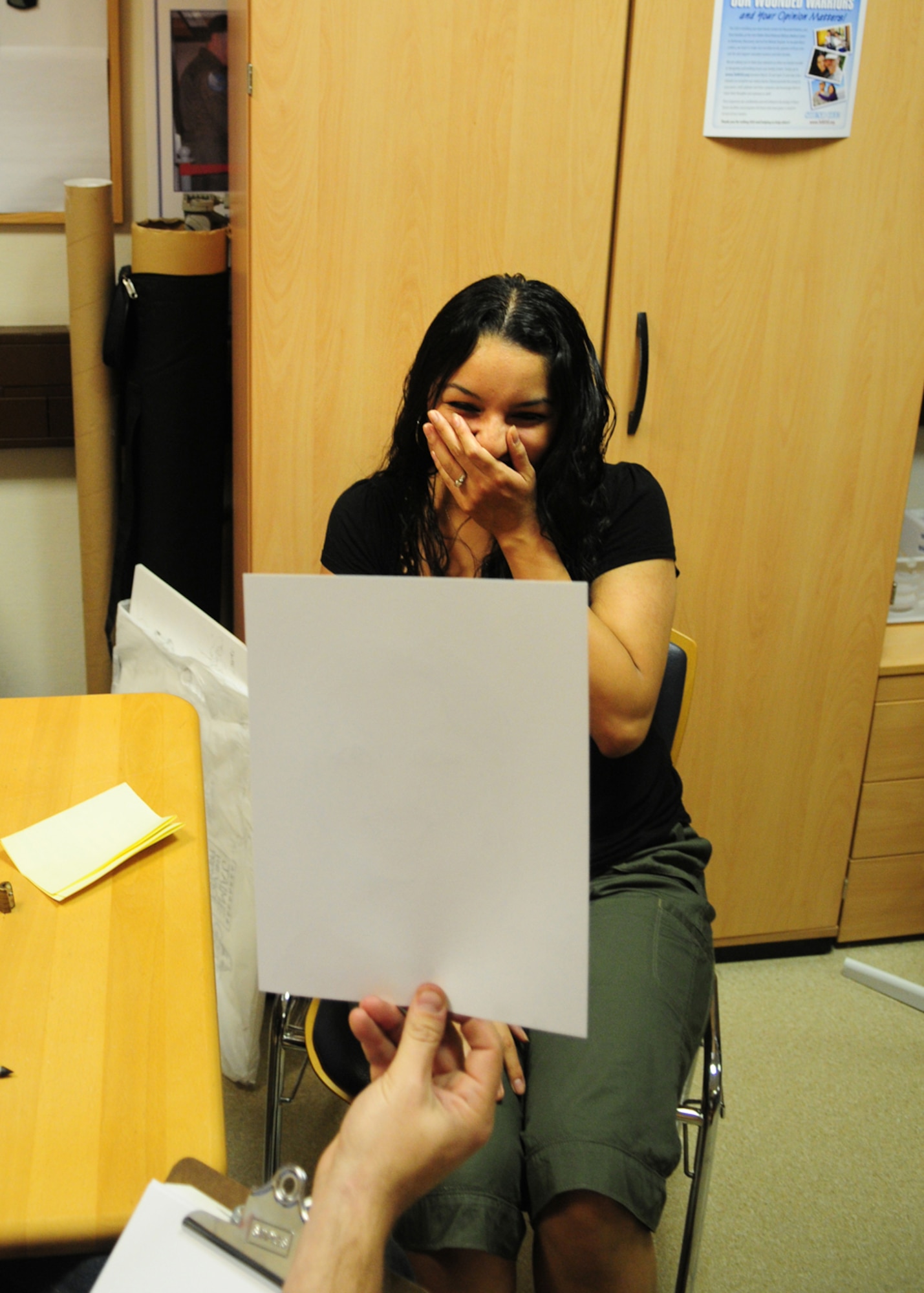 Veronica Garcilazo, United Services Organization (USO) information specialist, laughs about her caricature portrait at the USO in the Contingency Aeromedical Staging Facility, Ramstein Air Base, Germany, April 28, 2010. Several cartoonists took part in a two-day tour of the Kaiserslautern Military Community, visiting with wounded warriors, military members and their families (U.S. Air Force photo by Airman 1st Class Desiree Esposito)