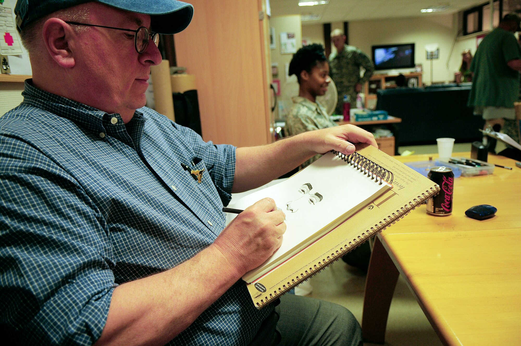 Cartoonist Bruce Higdon sketches a portrait of U.S. Air Force Senior Airman Micheal Jones, 86th Contingency Aeromedical Staging Facility medical technical, Ramstein Air Base, Germany, April 28, 2010. Several cartoonists took part in a two-day tour of the Kaiserslautern Military Community, visiting with wounded warriors, military members and their families. (U.S. Air Force photo by Airman 1st Class Desiree Esposito)