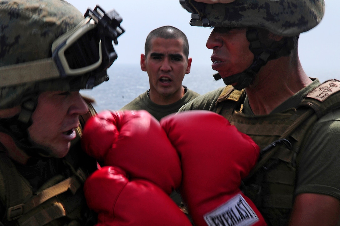 Sgt. Cesar Gonzalez observes Lance Cpls. Michael Kujath and Joshua A. Bossart, 15th Marine Expeditionary Unit, spar during conditioning exercises aboard amphibious assault ship USS Peleliu (LHA 5) Aug. 1, 2010, in the U.S. 5th Fleet area of responsibility.