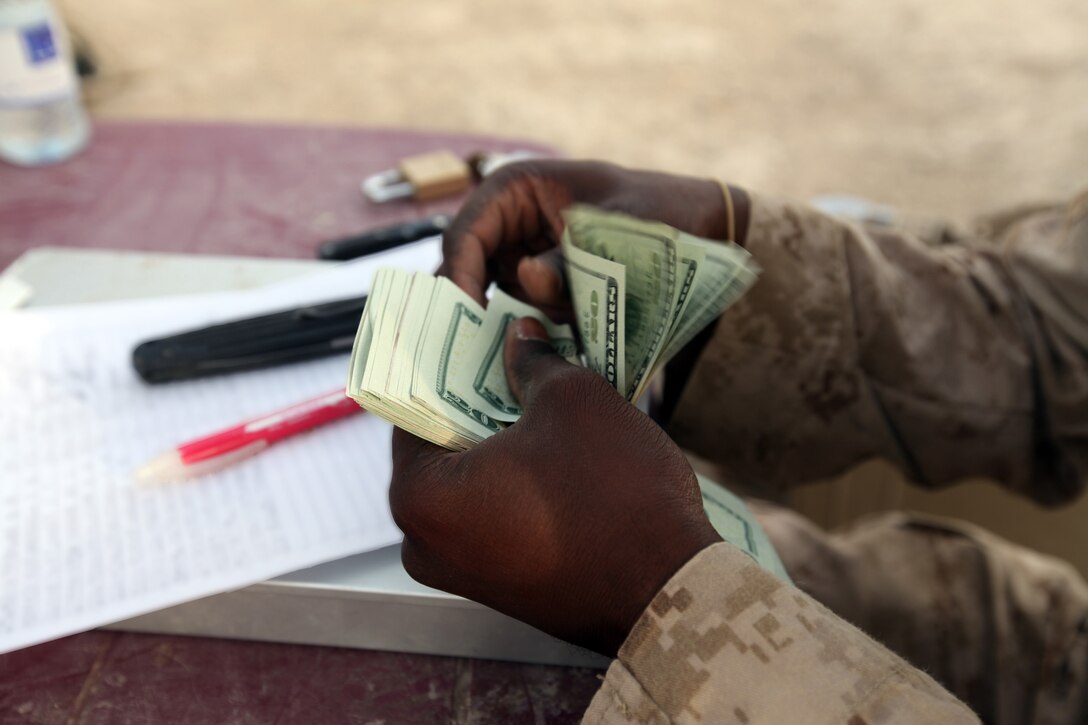 Cpl. Kofi Agyeman, disburser with Headquarters and Service Company, 1st Marine Logistics Group (Forward), issues casual pay to service members during a Warrior Express Services Team mission in northern Helmand Province, July 16-30. Service members conducting missions at forward operating bases and combat outposts don’t often have a chance to go to the Post Exchange or take cash out as these services aren’t readily available in remote areas, explained Agyeman, 24, from Wilmington, Del., a Ghanaian native.