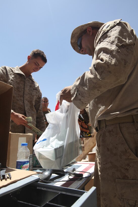 Sgt. Charles H. Mitchell IV, Marine Corps Community Services specialist with Headquarters and Service Company, 1st Marine Logistics Group (Forward), fills a bag with merchandise purchased by a Marine of 1st Battalion, 2nd Marine Regiment during a Warrior Express Services Team mission in northern Helmand Province, July 16-30. Mitchell, 33, from Carlsbad, Calif., believes that the services he provides to the service members boost their morale. ‘You show up and it’s kind of like being Santa Claus,’ he said. These service members were excited to see the mobile Post Exchange and disbursing Marines come to their area of operation.
