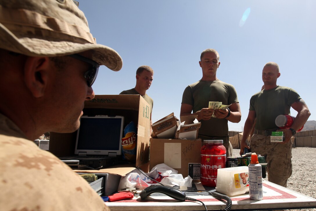 Sgt. Charles H. Mitchell IV, 33, from Carlsbad, Calif., Marine Corps Community Services specialist with Headquarters and Service Company, 1st Marine Logistics Group (Forward), works the cash register of a mobile Post Exchange, or PX, during a Warrior Express Services Team mission in northern Helmand Province, July 16-30. A WES Team consists of a disburser and a Marine Corps Community Services team. They provide service members conducting missions at remote forward operating bases and combat outposts a chance to take out some cash to purchase items from the mobile PX.