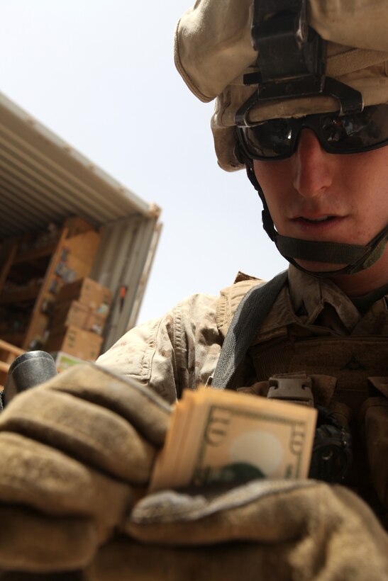 A Marine with 1st Battalion, 2nd Marine Regiment, counts his money to pay for a few comfort items at a mobile Post Exchange, or PX, during a Warrior Express Services Team mission in northern Helmand Province, July 16-30. A WES Team consists of a disburser and a team of Marine Corps Community Services specialists. They travel around combat outposts and forward operating bases in northern Helmand Province to provide services to Marines within the area of operation. The disbursing Marine allows service members to take out some cash while the MCCS team sets up a mobile PX and the Morale Satellite to allow service members to access the Internet in order to send messages to family and friends back home.