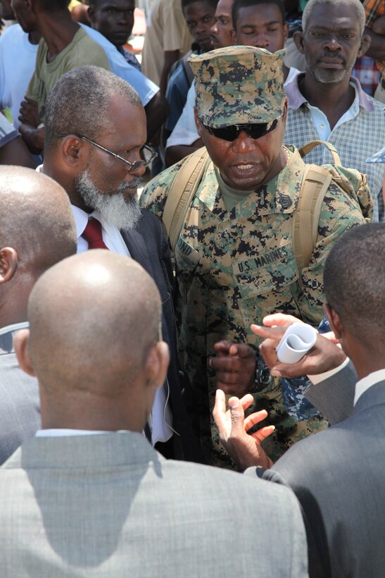 Gunnery Sgt. Felder Domond, a native of Port-au-Prince, Haiti, speaks with Guillet Salvador, mayor of Port-de-Paix, Haiti, left, and other key leaders of Haiti talk before the opening of the Friendship Ceremony in Port-de-Paix, Aug. 2, 2010. Domond served as a Creole translator for the USS Iwo Jima leaders and key leaders of Haiti. Marines and Sailors of the USS Iwo Jima spent ten days in Haiti as their first stop during their four-month deployment to the Caribbean, Central and South America.