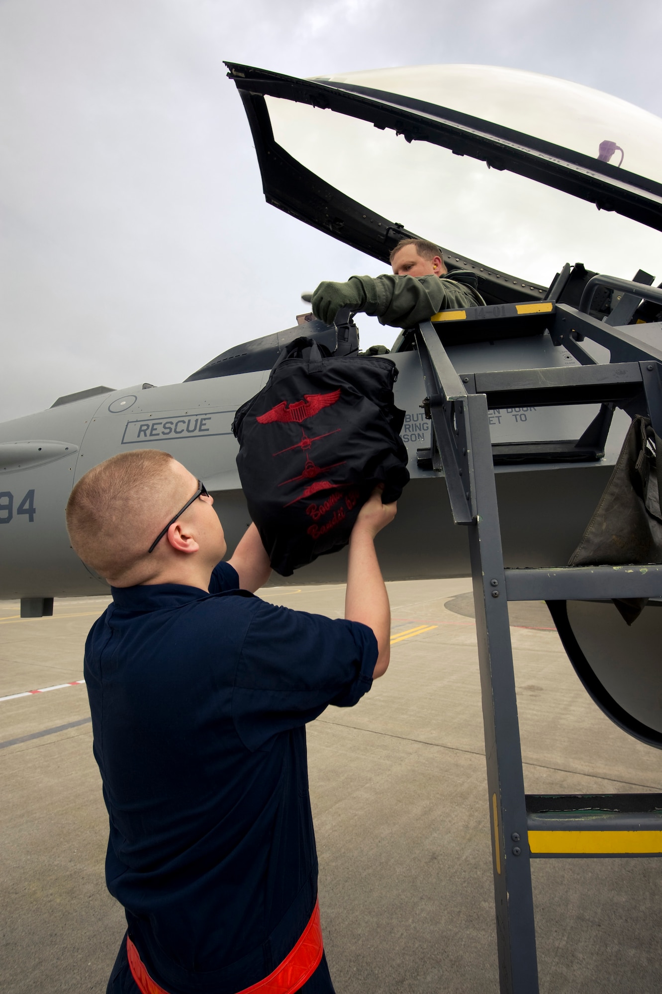 MISAWA AIR BASE, Japan -- Maj. John Greven, 13th Air Force Detachment 1, A5 plans and exercises officer, hands his flight bag to Airman 1st Class Patric Shaw, 13th Aircraft Maintenance Unit crewchief, following a training sortie Aug. 2. Stationed at Yokota Air Base, Major Greven visits Misawa to maintain his proficiency as an F-16 Fighting Falcon pilot. (U.S. Air Force photo/Staff Sgt. Samuel Morse)