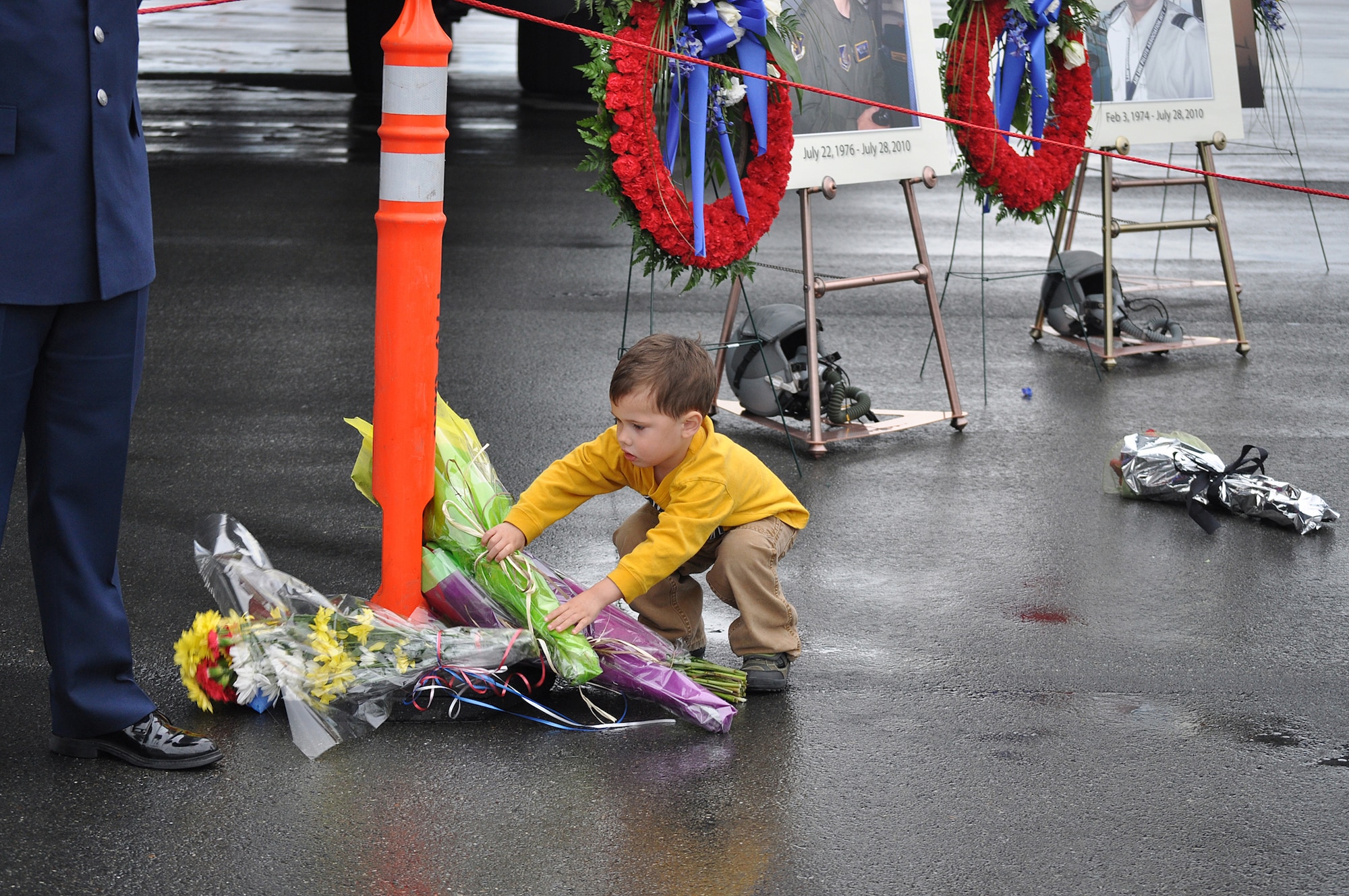 Three-year-old Emmett Parkison leaves a bundle of flowers at the memorial display for four aviators killed in the crash of Sitka 43. The display was set up in front of a C-17 at the Arctic Thunder Airshow Saturday, July 31,at Joint Base Elmendorf-Richardson. Sitka 43 crashed Wednesday, July 28. (Army photo by John Pennell/JBER PAO)