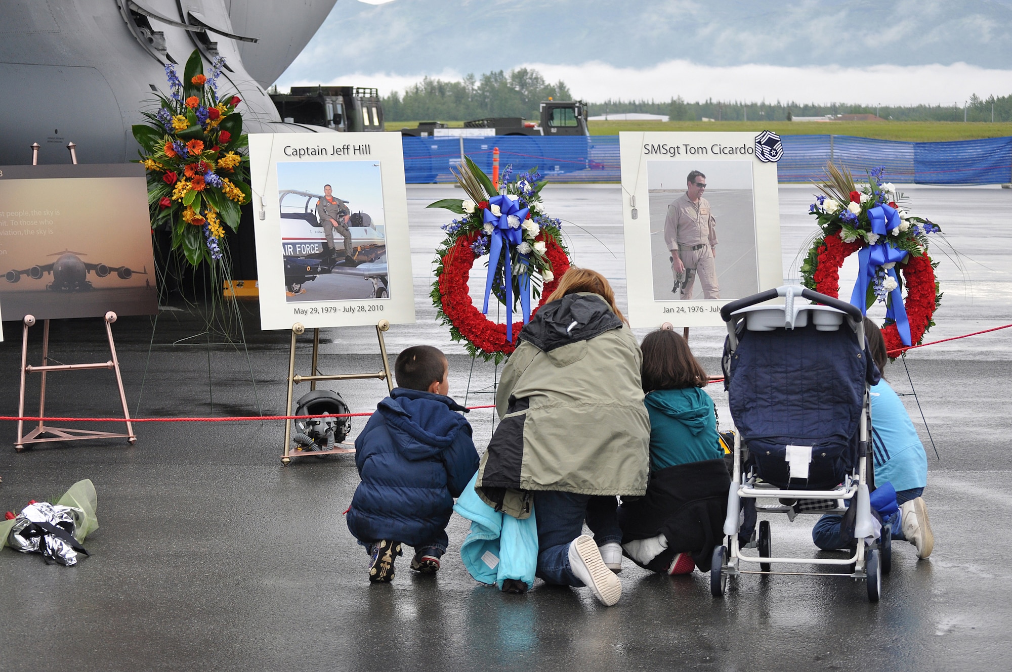 A family pauses at the Arctic Thunder Airshow Saturday, July 31,  in front of the memorial display for four aviators killed in the crash of Sitka 43 Wednesday, July 28. (Army photo by John Pennell/JBER PAO)