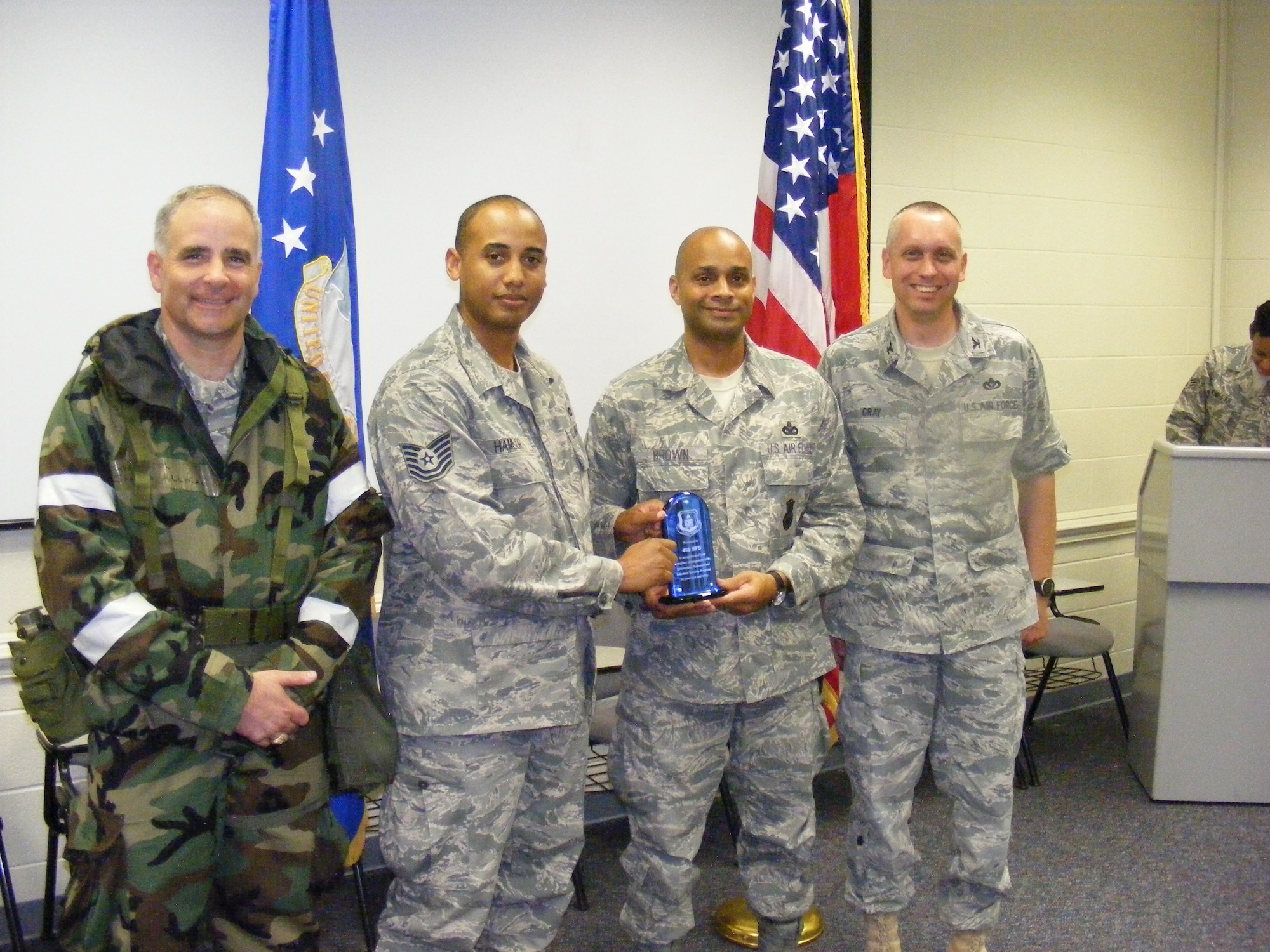 Tech Sgt. Bryant Hamlor (second from left) and Master Sgt. Richard Brown (third from left), 459th Security Forces Squadron, were recognized as the Team Andrews Unit Security Managers of the Quarter during the July 2010 Unit Training Assembly here. Col. James M. Allman (far left) 459th Air Refueling Wing commander, presented the award during Chemical and Biological Warfare training. The award recognizes the security forces Airmen during Jan. 1 to Mar. 31 2010 for strongly managing information, personnel and industrial security programs. (U.S. Air Force photo)