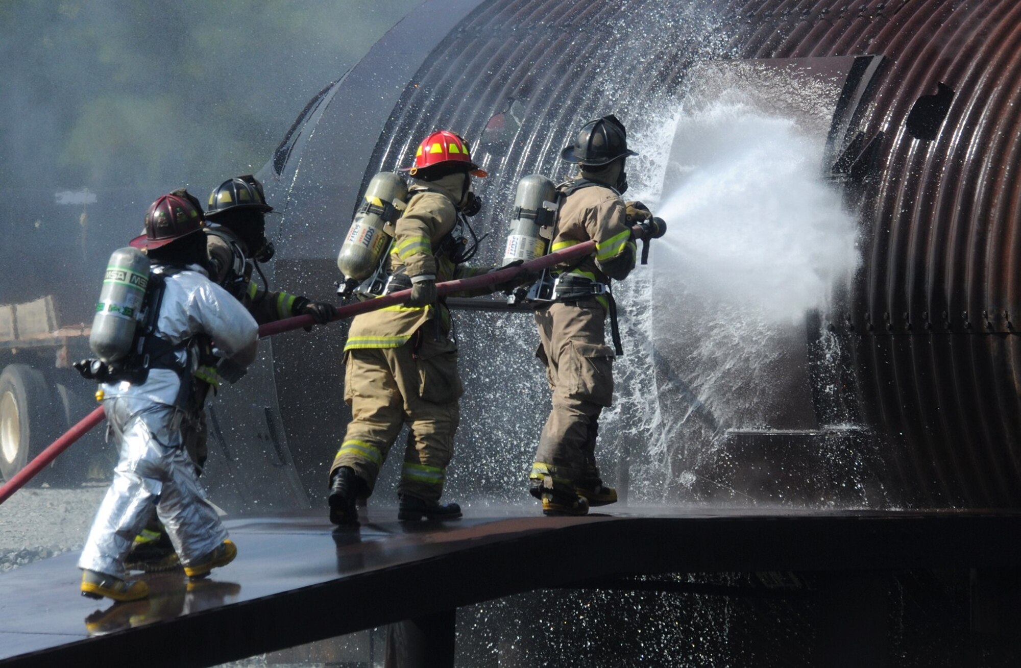 MOODY AIR FORCE BASE, Ga. -- A four-man team from the Valdosta Fire Department move together to extinguish an internal flame during a live fire training exercise here July 27. The Valdosta Fire Department, along with the Southwest Georgia Regional Airport response team from Albany, Ga., brought nearly 30 members to participate in the training with the 23rd Civil Engineer Squadron fire emergency services flight. (U.S. Air Force photo by Airman 1st Class Benjamin Wiseman/RELEASED)