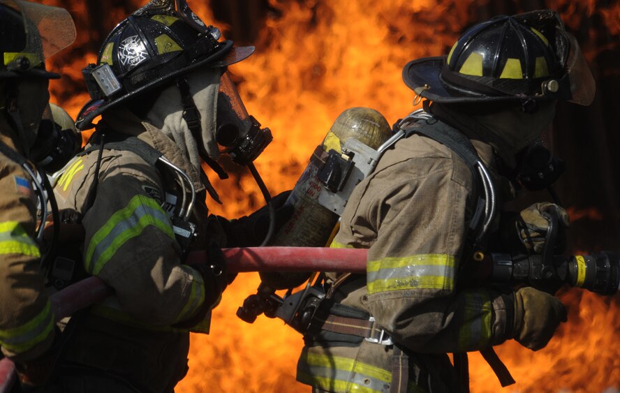 MOODY AIR FORCE BASE, Ga. -- Isaac Harris and Carolyn McMillan, Valdosta Fire Department engineers, use a 1.75-inch hose to fight a ground fire during a live fire training exercise here July 27. Mr. Harris held the nozzle and directed the flow of water as Ms. McMillan supported him from behind. (U.S. Air Force photo by Airman 1st Class Benjamin Wiseman/RELEASED)
