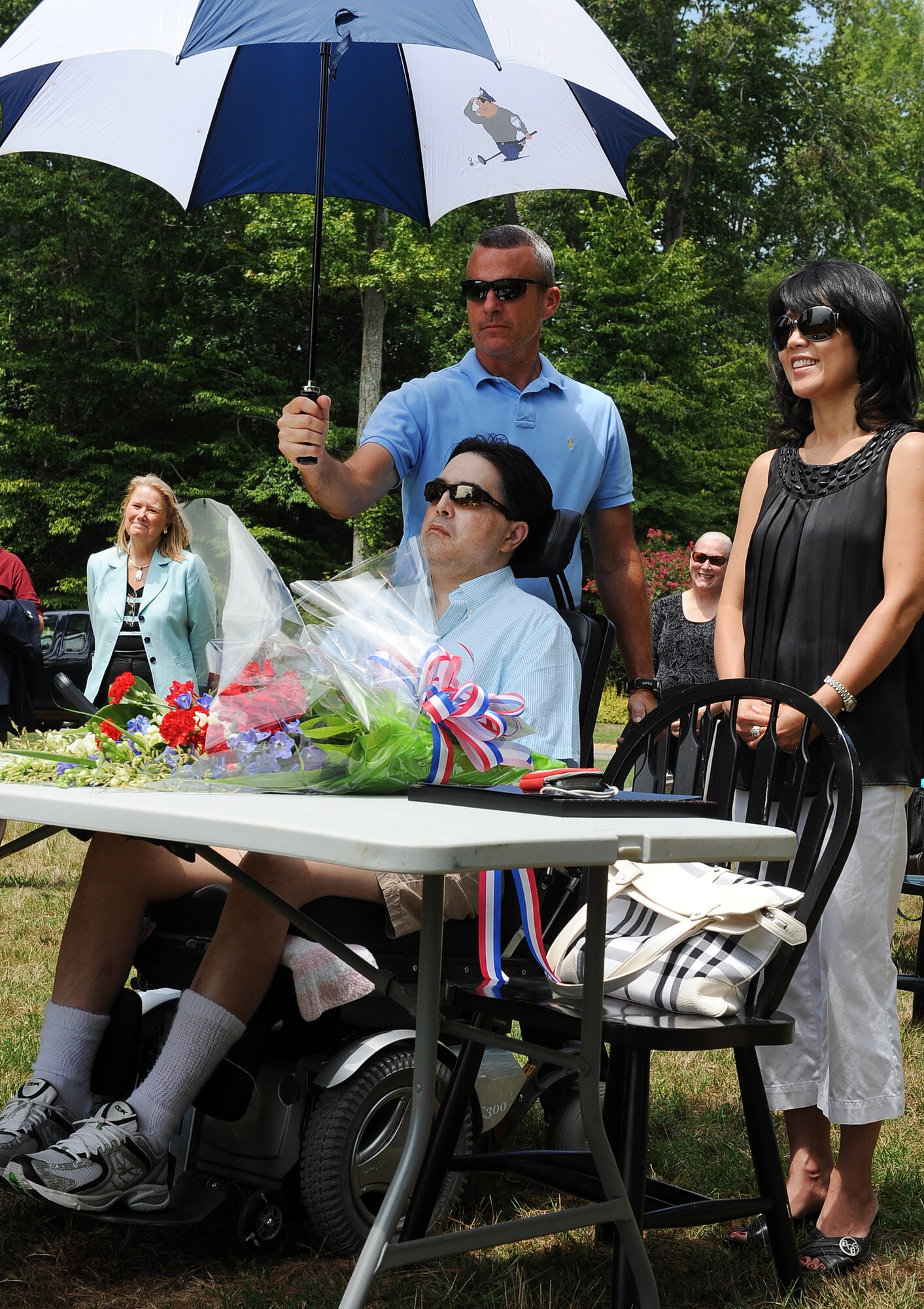 LANGLEY AIR FORCE BASE, Va. -- Lt. Col. (ret.) Earl Gentile, his wife Julie Gentile and Donald Overton, friend of the family listen to the orator during a ground breaking ceremony July 31. Lt. Col.  Gentile, who is confined to a wheel chair due to multiple sclerosis, was helped by the Disabled Veterans Committee on Housing build a home. This organization helps disabled veterans receive grants up to $63,780 from the Department of Veterans Affairs to build, purchase or remodel their homes. (U.S. Air Force photo/ Senior Airman Gul Crockett)