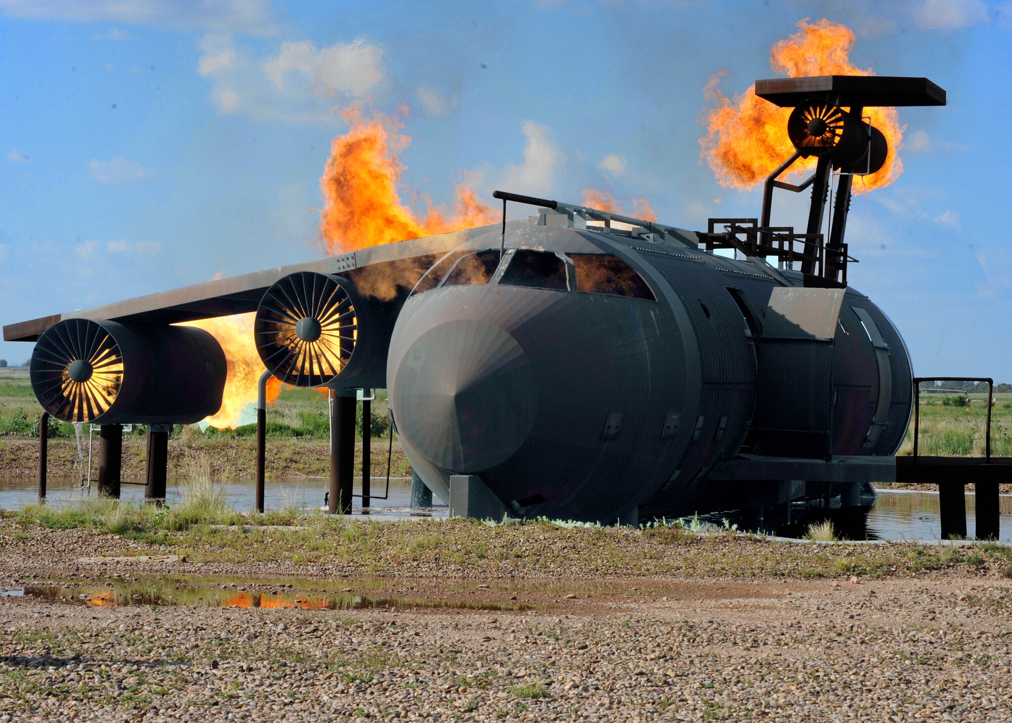 An old modified aircraft provides Cannon Air Force Base, N.M., firefighters opportunities to train on various types of blazes. Members from the Clovis, N.M. Fire Department fulfilled their annual requirements for aircraft fire training July 26 on the propane-fueled hulk.  (U.S. Air Force photo by Greg Allen) 
