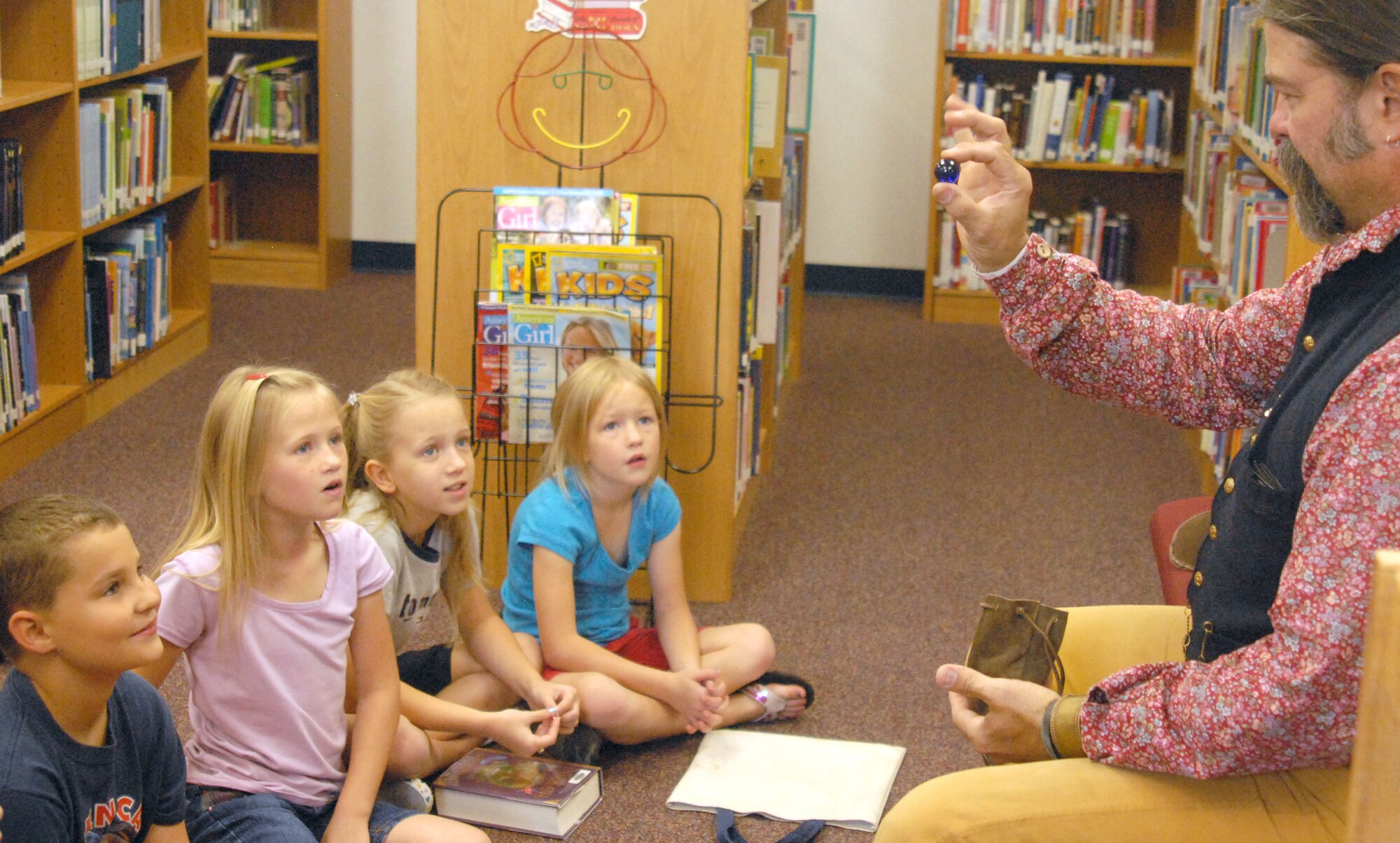GOODFELLOW AIR FORCE BASE, Texas -- Christopher Morgan, a guest speaker from Fort Concho, shows children the toys youths played with in the 1870s as part of a summer reading program at the library here. Mr. Morgan is also dressed in traditional clothing of the late 19th century. (U.S. Air Force photo/Airman 1st Class Jessica D. Keith) 