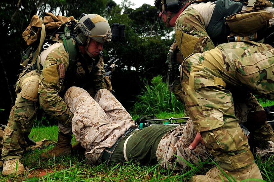 Senior Airman Daniel Flechsenhaar (left), Pararescuemen from the 31st Rescue Squadron, and Senior Airman Andrew Nichols, Pararescuemen from the 31st Rescue Squadron, lift a Marine during a simulated attack on Kadena Air Base July 28. The 31st and 33rd Rescue Squadrons supported the Marine mission due to an upcoming deployment for the rescue squadrons. (U.S. Air Force photo by Senior Airman Amanda N. Grabiec)