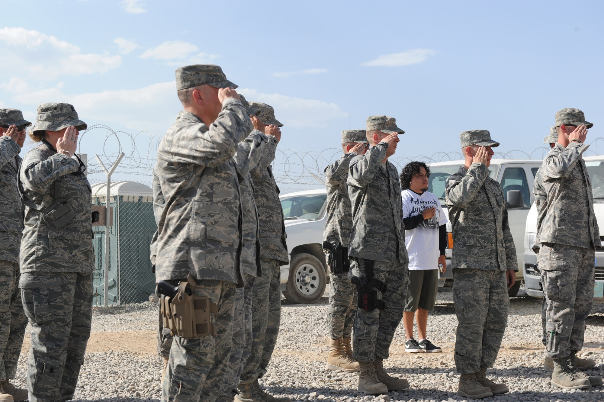 Members and guests of the 455th Expeditionary Logistics Readiness Squadron salute during the singing of the national anthem at Bagram Airfield, Afghanistan. They were gathered here to witness the dedication of the Vehicle Operations Control Center to the memory of Senior Airman Ashton Lynn Marie Goodman. (U.S. Air Force Photo/Maj. John Puckett)