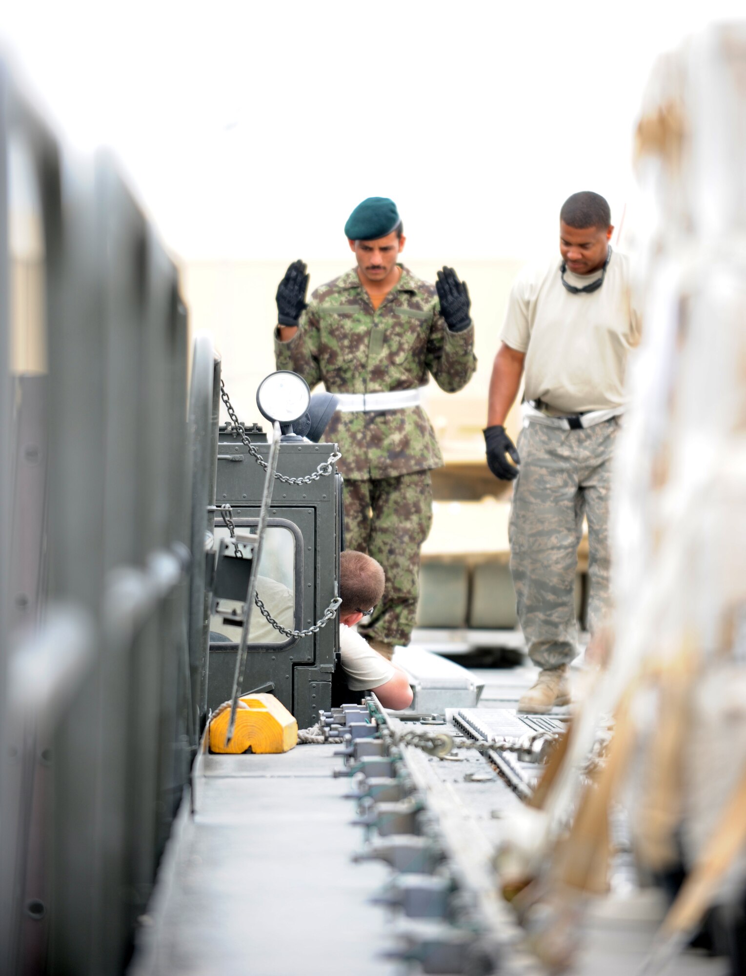 Staff Sgt. Vincent Ross, an aerial porter with the 455th Expeditionary Aerial Port Squadron, trains an Afghan aerial porter to safely guide a 60K Tunner Cargo Loader  toward its intended cargo. (U.S. Air Force photo/Tech. Sgt. Drew Nystrom)