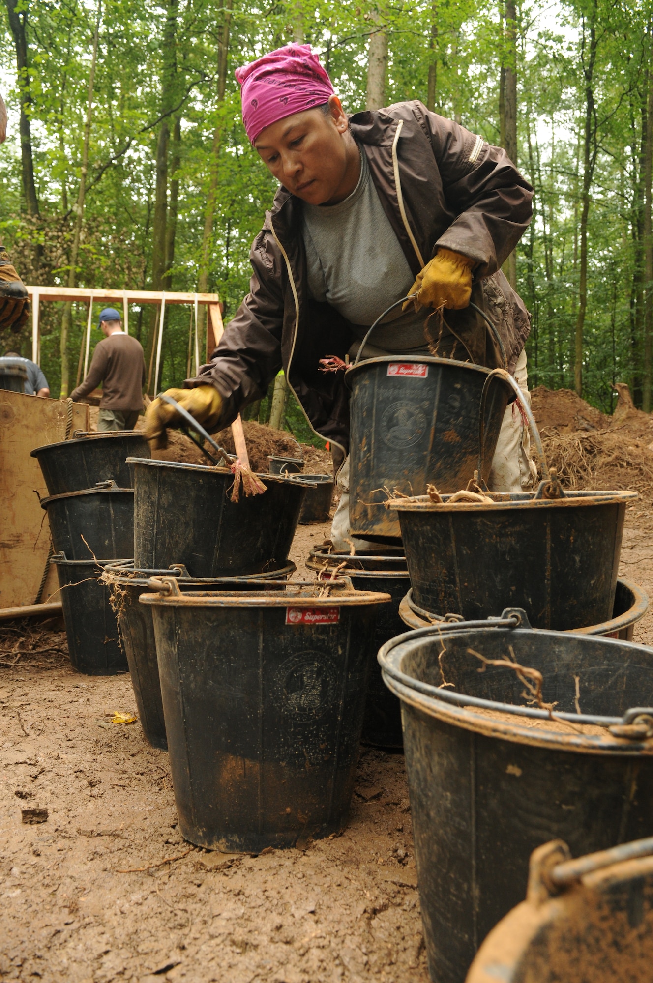 RHEINLAND-PFALZ, Germany – Master Sgt. Victoria Querido, Joint Prisoners of War/Missing in Action Accounting Command, moves buckets of dirt from the excavation point to sifting stations July 28. The dirt was sifted in search of wreckage from an aircraft downed during World War II. (U.S. Air Force photo/Staff Sgt. Benjamin Wilson)