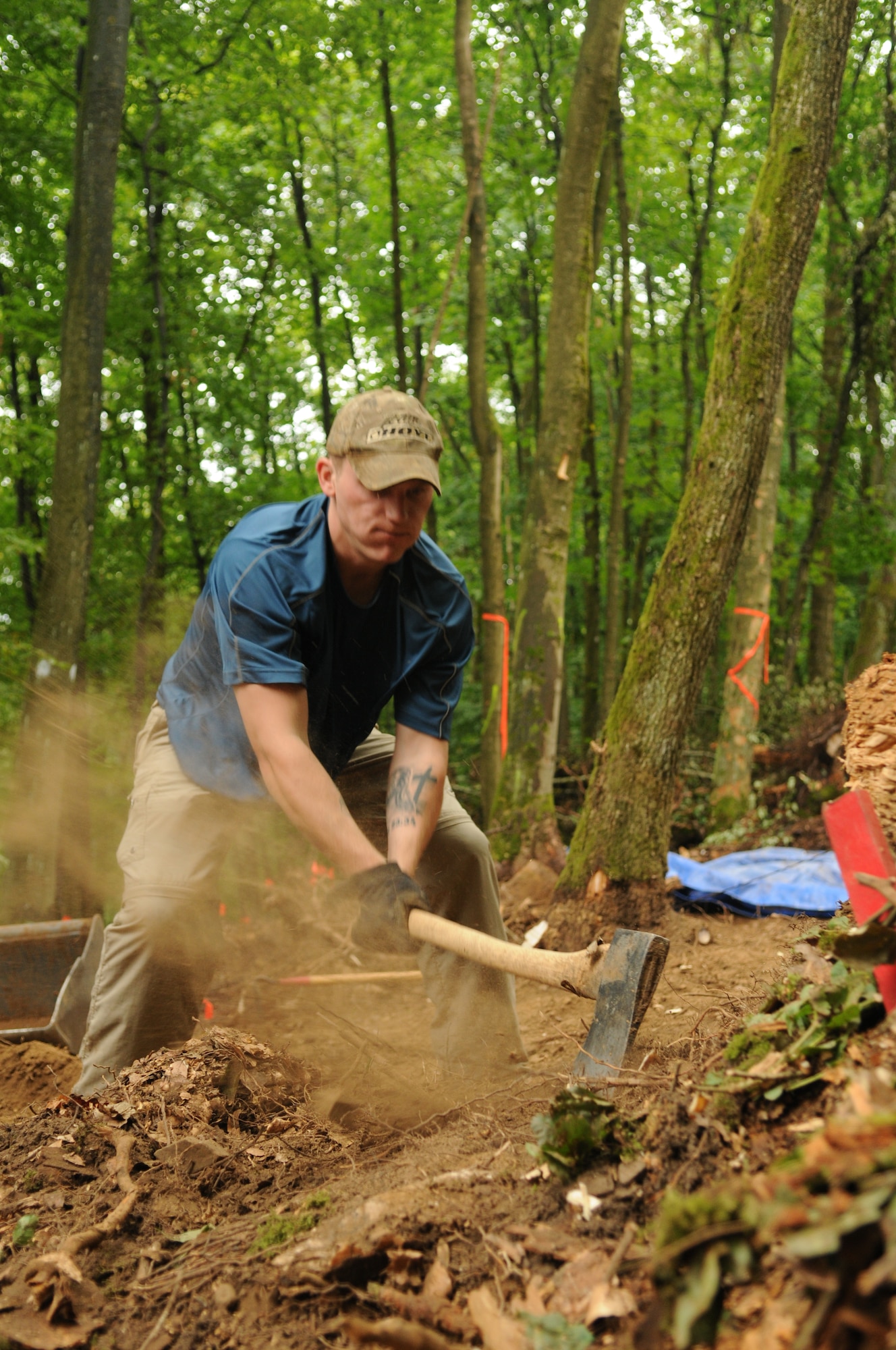 RHEINLAND-PFALZ, Germany – Army Sgt. Mathew Hyde, Joint Prisoners of War/Missing in Action Accounting Command, chops through a root to clear the ground for excavation July 28. The ground was dug up in search of wreckage from an aircraft downed during World War II. (U.S. Air Force photo/Staff Sgt. Benjamin Wilson)