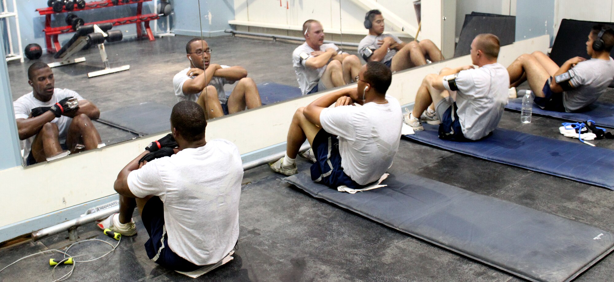 Airmen complete crunches in almost perfect sync in the Red Tail Fitness Center July 27, 2010, Joint Base Balad, Iraq.  Airmen do these and other exercises to prepare for PT tests and improve their overall fitness. The Red Tail has numerous areas where anyone can do crunches, pushups, jump rope and more. (U.S. Air Force photo/Staff Sgt. Stacy Fowler)
