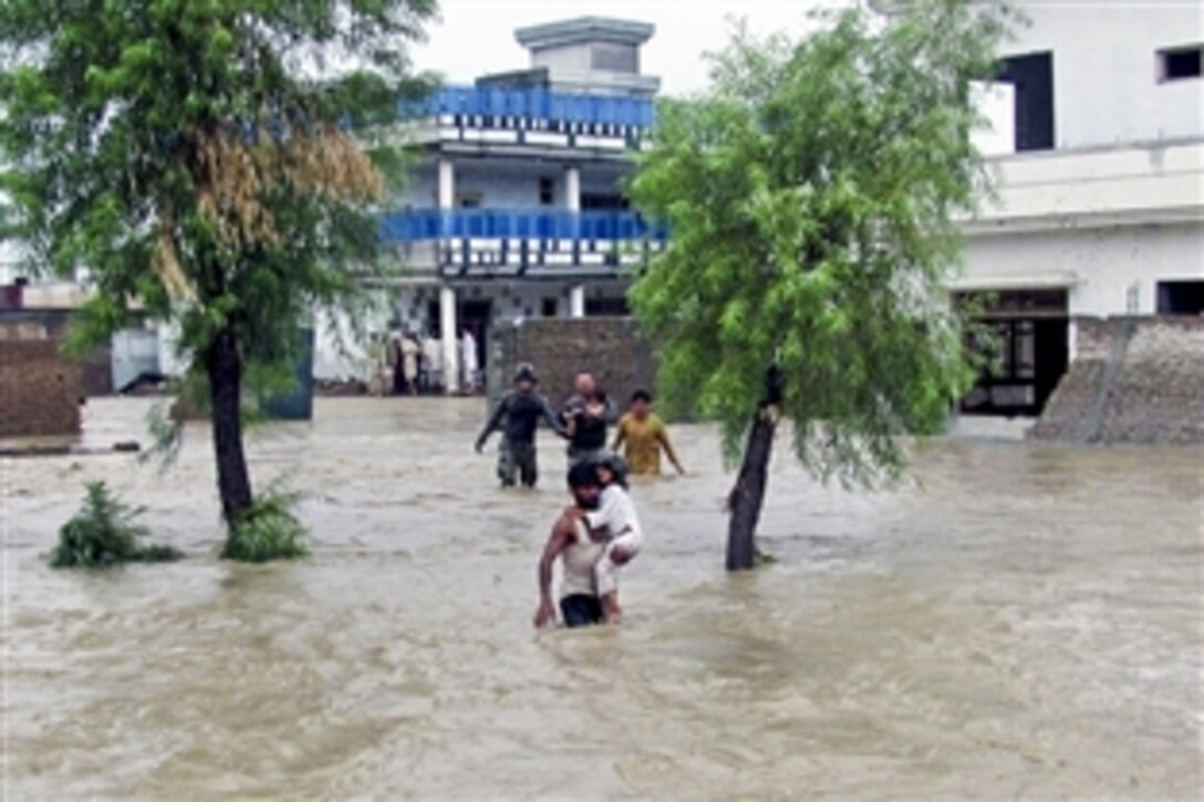 U.S. Army Cpl. Patrick O’ Rourke, left, and U.S. Army Sgt. Robert Huff help local Afghans reach safety away from encroaching flood waters in the Nari Shahi village in the Beshood district of eastern Afghanistan's Nangarhar province, July 28, 2010. The flooding was caused when more than six inches of rain fell in a few hours. O' Rourke and Huff are assigned to the Military Police Platoon, Headquarters Company, Special Troops.