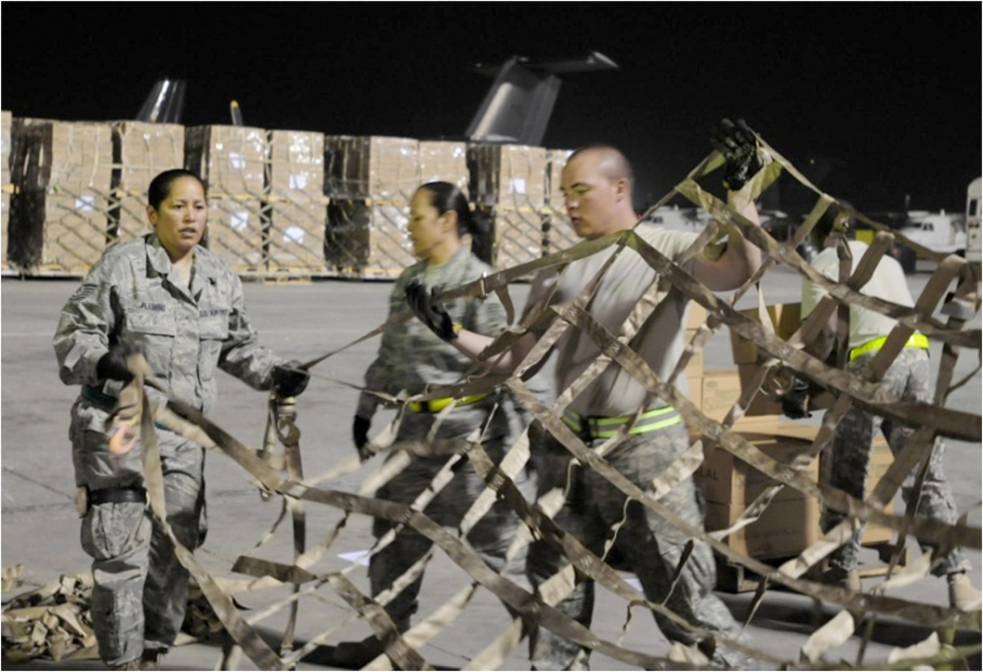 Tech. Sgt. Cheryl Flemming instructs a pallet-building team on how to prepare a cargo net for placement over a completed pallet Aug. 2, 2010, at Bagram Airfield, Afghanistan, to ensure its contents don't shift during flight. The pallet contains some of the 345 thousand halal meals that have been delivered to northwest Pakistan since July 31, 2010, as part of the humanitarian flood relief assistance provided to the area that's been hit by monsoon rains in recent days. Sergeant Flemming is the 455th Aerial Port Squadron Air Terminal Operations Center quality and control NCO in charge. (U.S. Air Force photo/Capt. Chris Sukach)