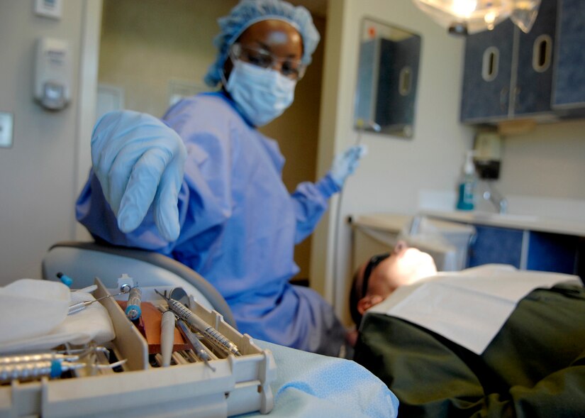 Staff Sgt. Ebony Holt reaches for a dental instrument while cleaning a patient's teeth at the Deily Dental Clinic June 8, 2010, on Joint Base Charleston, S.C. The purpose of the cleaning and polishing is to leave the surfaces of the teeth clean and smooth so bacteria is unable to stick, leaving the patient with a better chance of keeping their teeth clean during regular home care. Sergeant Holt is a dental assistant with the 628th Medical Group. (U.S. Air Force photo/Senior Airman Timothy Taylor)