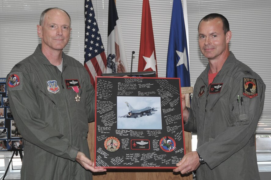 Operations Group Commander, Col. Kevin Heer (right), presents retiring 132nd Fighter Wing Commander, Col. Mark Hammond (left), with his retirement mat (signed by pilots of the 124th Fighter Squadron) during his retirement ceremony held in the 132nd Fighter Wing Dining Facility, Des Moines, Iowa, on July 11, 2010.  Col. Hammond is retiring with over 26 years of service to his country.  He has had numerous assignments since he enlisted in 1984, and became the 132nd Fighter Wing Commander in May of 2007.  (US Air Force photo/Staff Sgt. Linda E. Kephart)(Released)