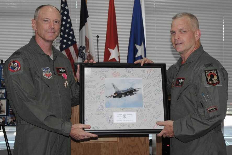 132nd Fighter Wing Commander, Col. Drew DeHaes (right), presents retiring 132nd Fighter Wing Commander, Col. Mark Hammond (left), with his retirement mat (signed by 132nd Fighter Wing members) during his retirement ceremony held in the 132nd Fighter Wing Dining Facility, Des Moines, Iowa, on July 11, 2010.  Col. Hammond is retiring with over 26 years of service to his country and has had numerous assignments since he enlisted in 1984.  He became the 132nd Fighter Wing Commander in May of 2007, and has relinquished command to Col. DeHaes effective 1 May 2010.  (US Air Force photo/Staff Sgt. Linda E. Kephart)(Released)