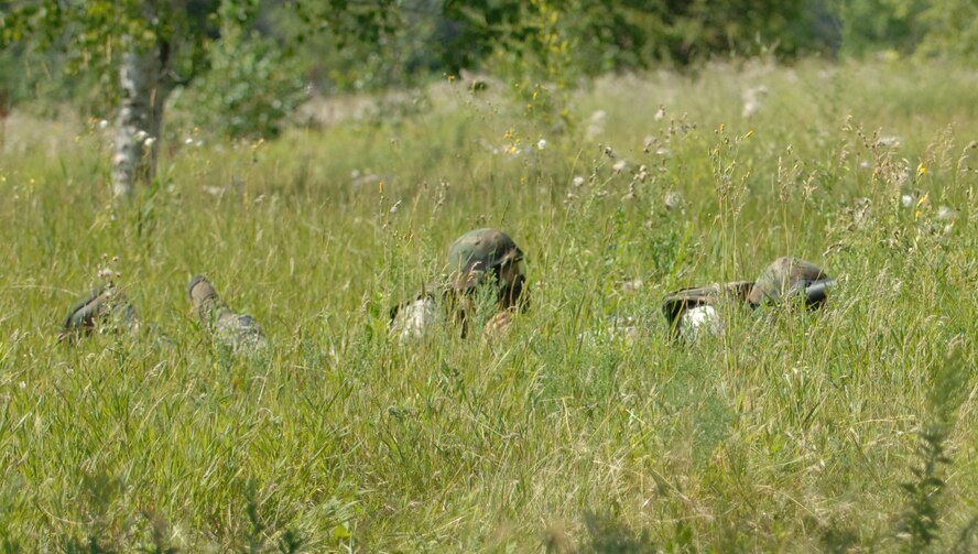 Senior Airmen Aaron Smith and  Manuel Langstraat, both 319th Security Forces Squadron installation entry controllers, high crawl toward cover during a game of capture the flag, part of the annual combat readiness training Aug. 2 at the Grand Forks Air Force Base paintball course. The mandatory training included a refresher course in evasive maneuvers and tactical movement, and culminated in a demonstration of skills during a game of paintball. (U.S. Air Force photo by Airman 1st Class Rachel Martinez)