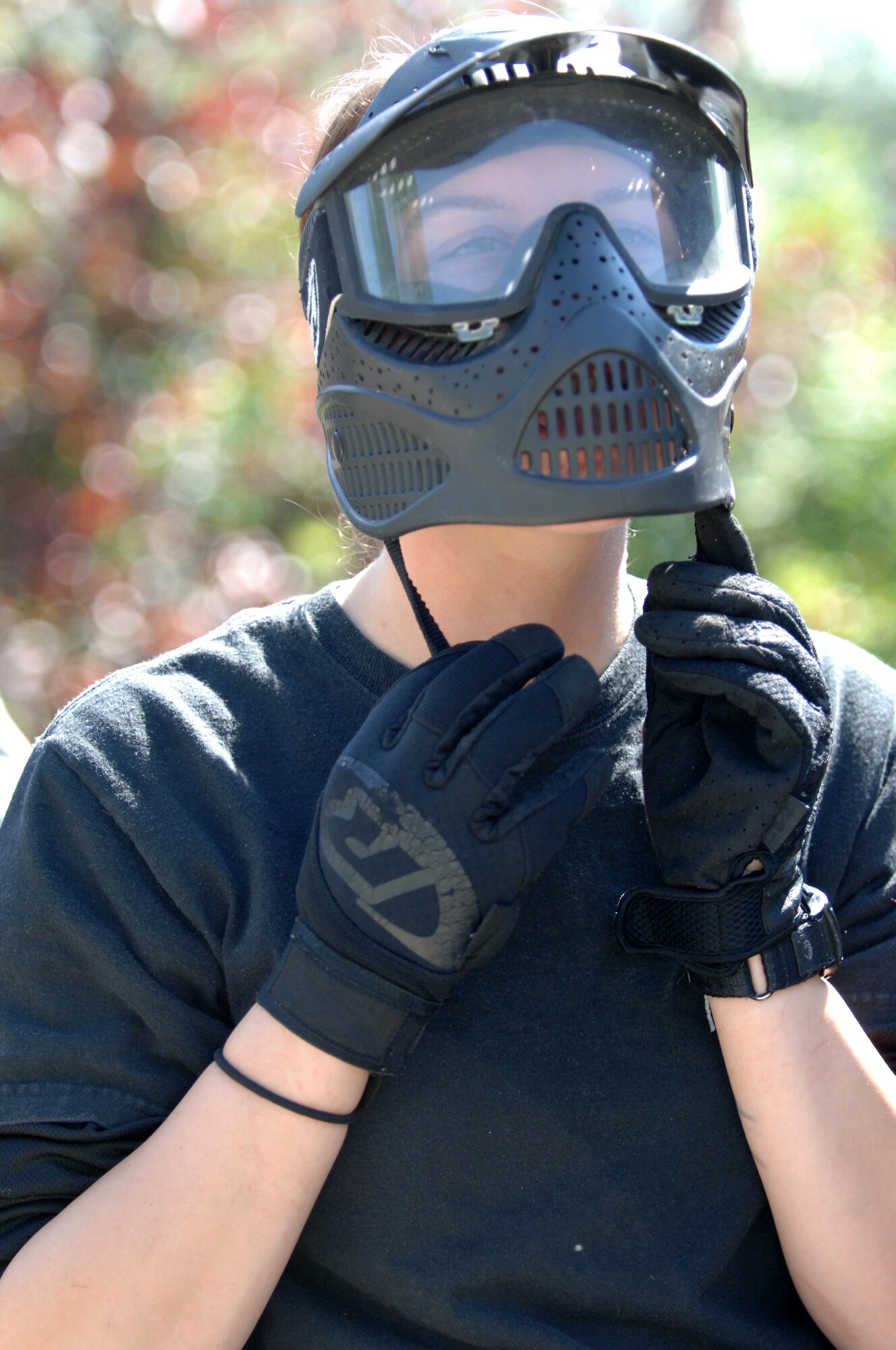 Airman 1st Class Amber Murphy, 319th Security Forces Squadron installation entry controller, clips a protective mask into place before participating in the annual combat readiness training Aug. 2 at the Grand Forks Air Force Base paintball course. The mandatory training included a refresher course in evasive maneuvers and tactical movement, and culminated in a demonstration of skills during a game of paintball. (U.S. Air Force photo by Airman 1st Class Rachel Martinez)