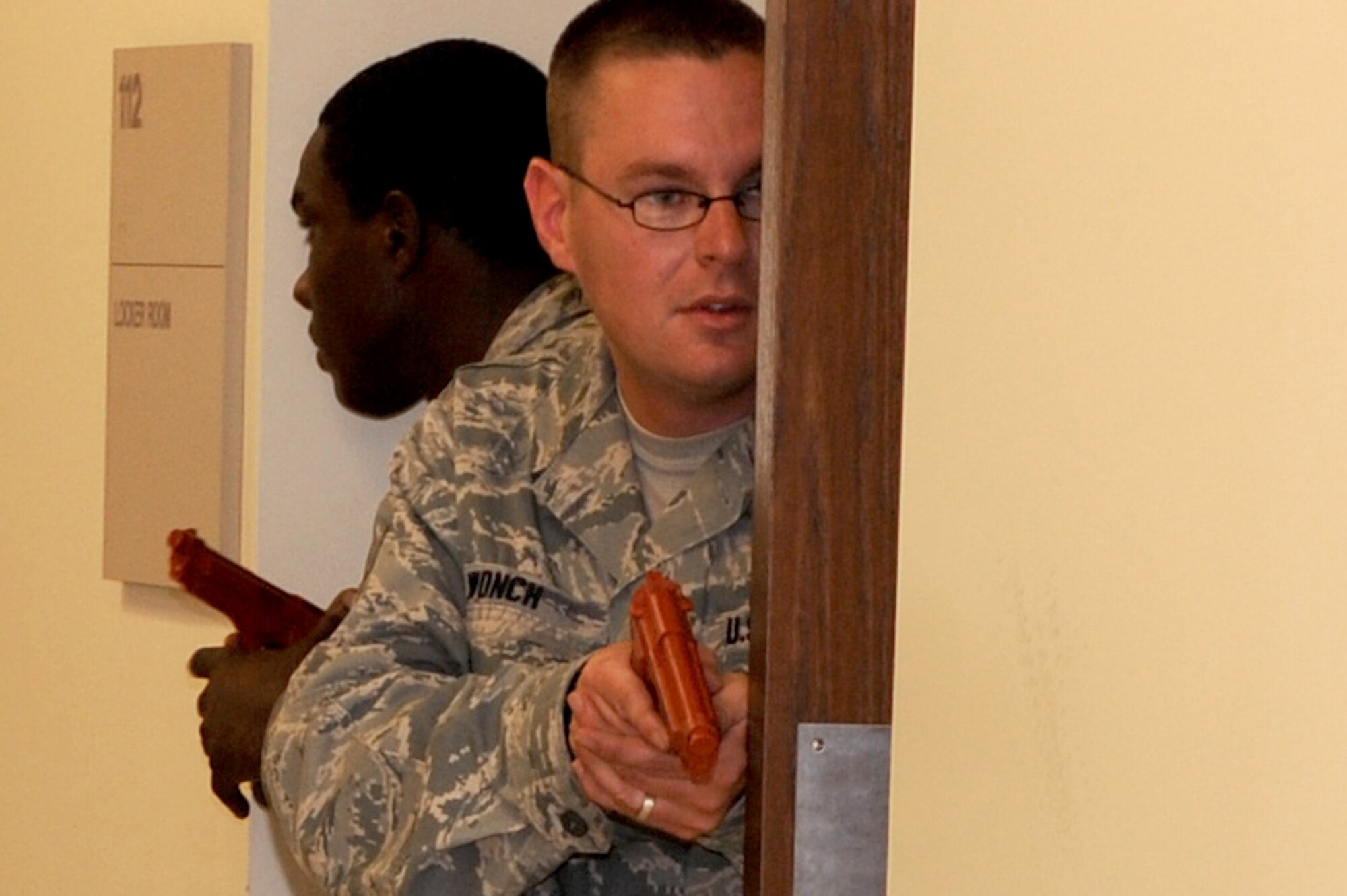 Staff Sgt. Kevin Wonch, 375th Security Forces Squadron, watches the hallway as  his team clears a room  during a simulated disturbance call during a training exercise at Scott AFB, July 21, 2010. The exercise is designed to prepare all security forces officers for any situation when entering a reported disturbance scene. (U.S. Air Force photo by Staff Sgt. Brian J. Ellis)