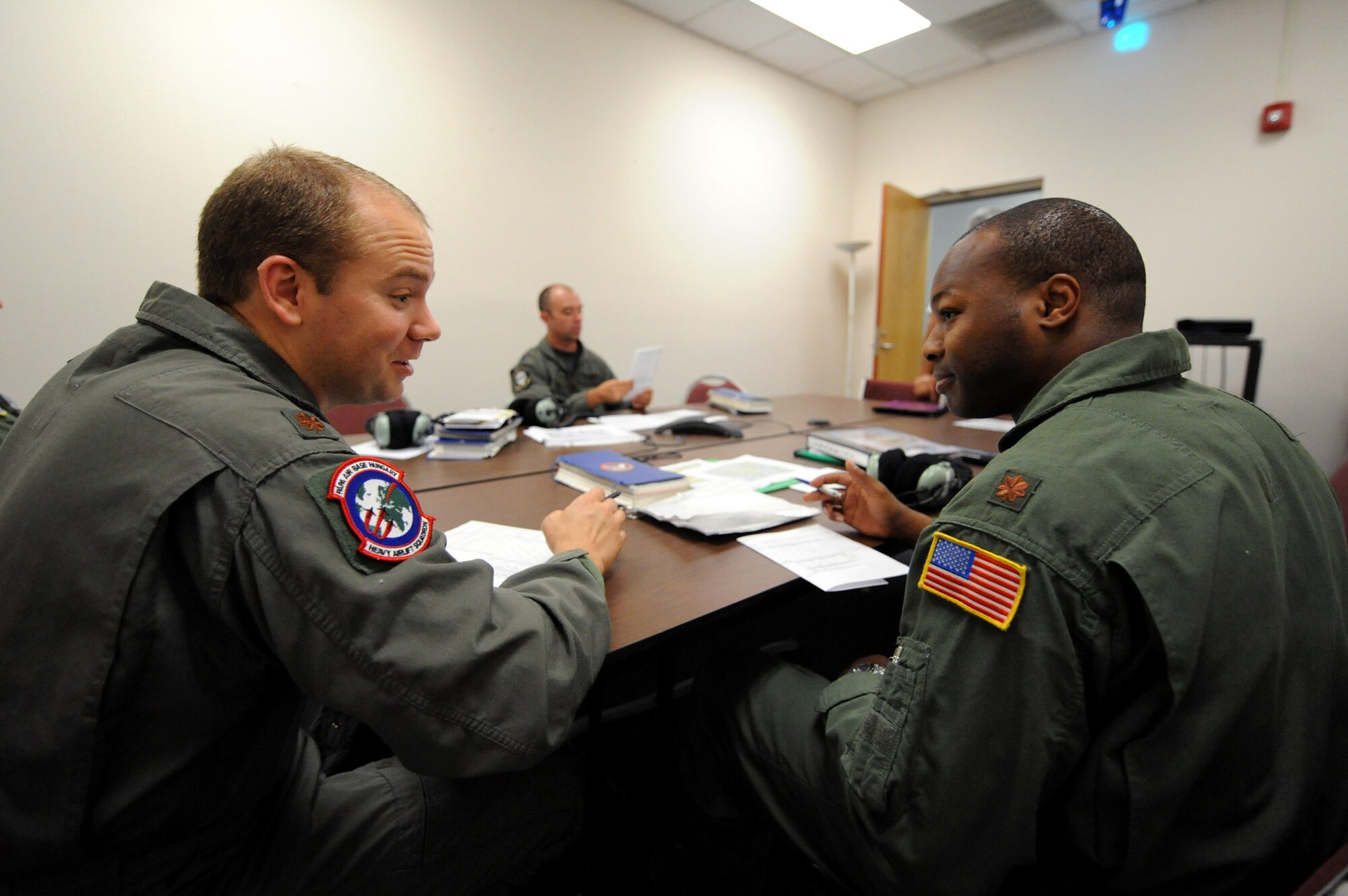 Maj. Brian Nicosia discusses details on flight plans with Maj. Patrick Brady-Lee prior to flying in the C-17 Globemaster III simulator June 21, 2010, on Joint Base Charleston, S.C. Major Nicosia is the chief of tactics with the Heavy Airlift Wing at Papa Air Base, Hungary, and is visiting Joint Base Charleston for quarterly pilot training. (U.S. Air Force photo/James M. Bowman)