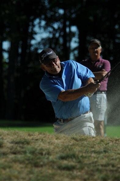 NH Air National Guard Master Sergeant William Gammon hits his golf ball out of a bunker during the 46th Annual NH National Guard Golf Classic 2010 tournament held at The Oaks golf link, Somersworth, NH, July 26, 2010.  Master Sergeant (retired)  Earl Andrews watches from the background.  (released/photo by Aaron P. Vezeau