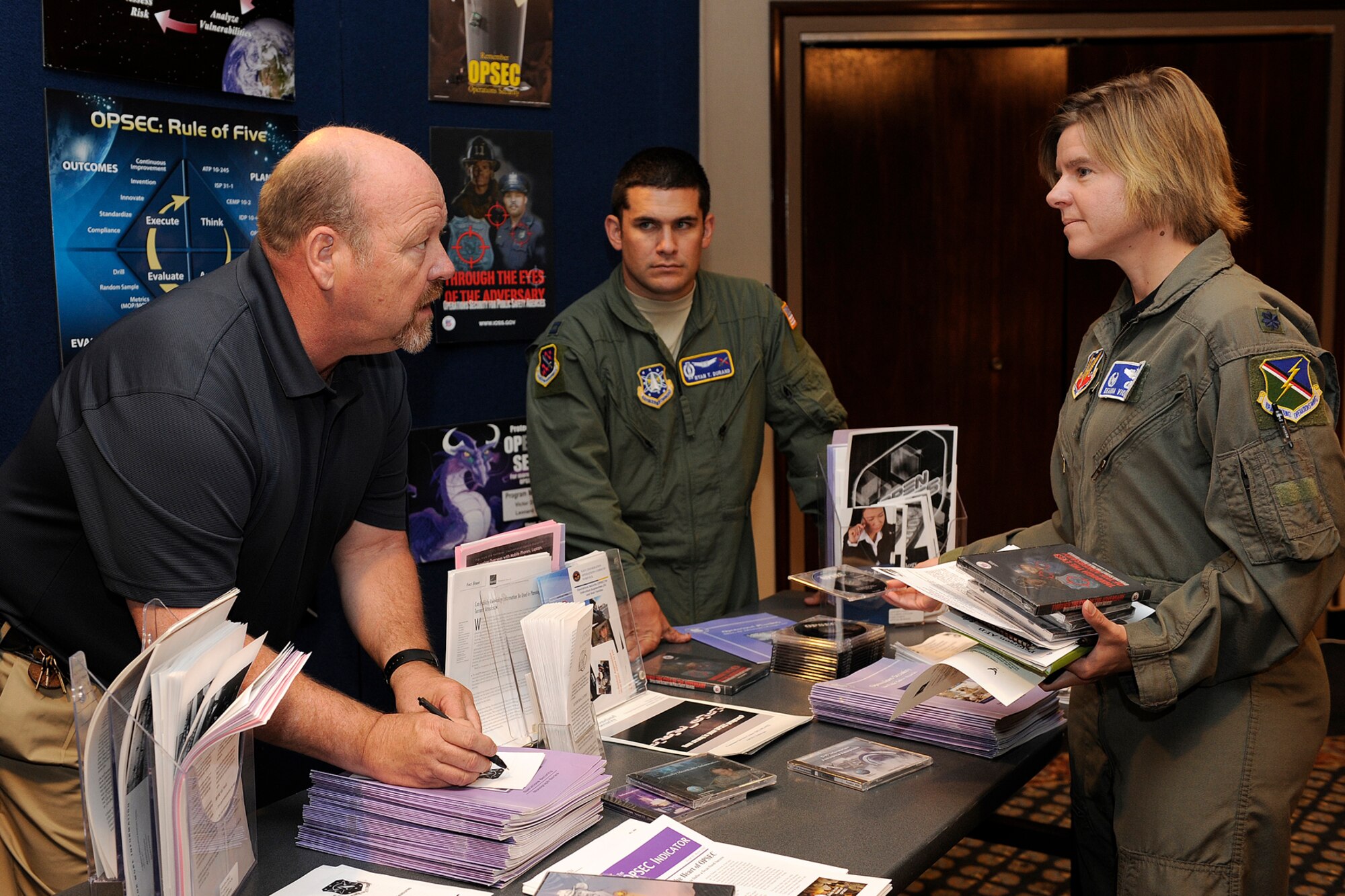 PETERSON AIR FORCE BASE, Colo. – Lt. Col. Deanna L. Violette, 13th Air Support Operations Squadron commander, Fort Carson, gathers DVDs and pamphlets from the Operations Security booth during the 21st Space Wing Mission Partner Focus Day July 27 at The Club. This event, hosted by Col. Stephen N. Whiting, 21st Space Wing commander, brought in experts from across the wing to provide information and key contact information for the wing’s mission partners. Mission partners heard from 20 experts including personnel from the 21st Force Support Squadron about the new Air Force fitness standards and 21st Security Forces Squadron on the Defense Biometric Identification System and the new integrated defense policing concepts. They learned about key deadlines and timelines for acquisitions. The mission partner focus day also included an information fair and a round table discussion. (U.S. Air Force photo/Craig Denton)