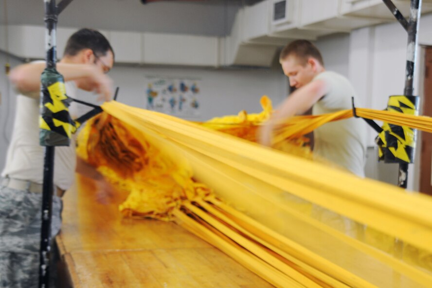 BARKSDALE AIR FORCE BASE, La. -- Staff Sgt. Wesley Vinson and Airman 1st Class Matthew Treguboff, 2d Operational Support Squadron aircrew flight equipment technicians, ensure that the lines of a B-52 drag-chute are untangled to ensure proper release July 29. A drag-chute is an extra-large parachute that B-52 pilots deploy during landing to slow the aircraft's momentum. (U.S. Air Force photo by Senior Airman Brittany Y. Bateman)(RELEASED) 