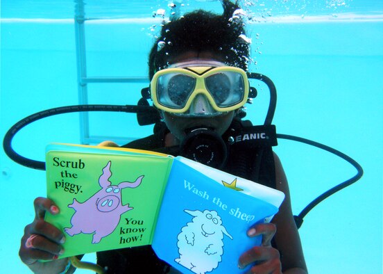 Jessica Busch reads a book underwater during a summer reading event at the base pool on July 24. (Photo by Dorothee Bennett)