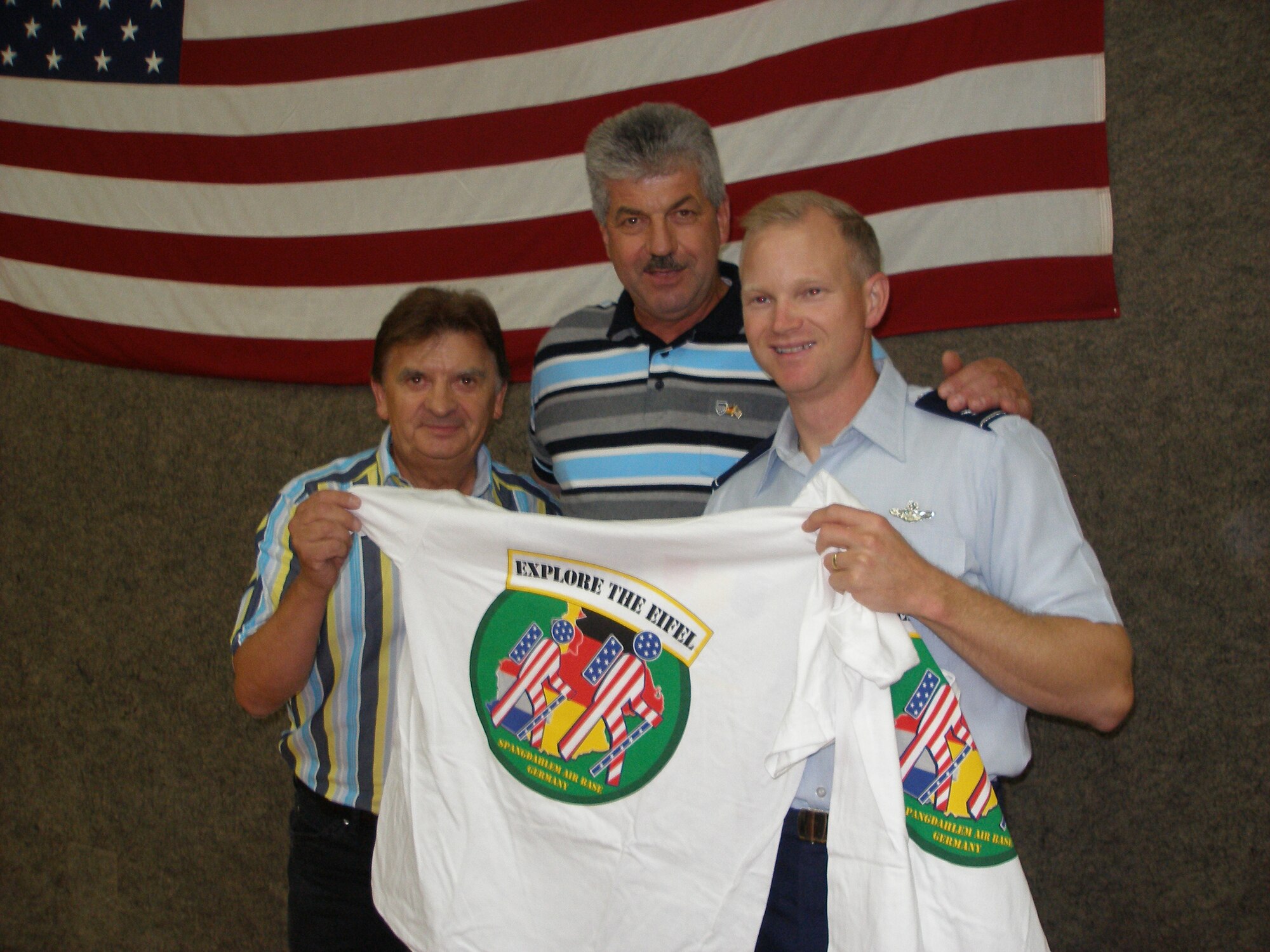 The mayor of Spangdahlem, Klaus Rodens (middle), and the honorary commander of the 81st Aircraft Maintenance Squadron Aircraft Maintenance Unit, Ewald Stuckart, both present an Explore the Eifel T-shirt to the 52nd Fighter Wing commander, Col. Christopher Weggeman. (Courtesy photo by Hillarius Esch)