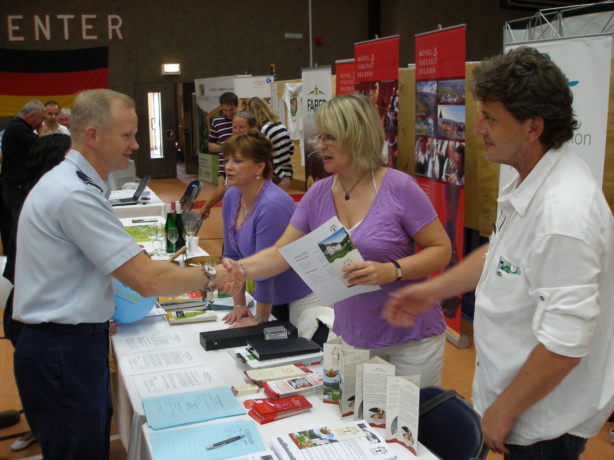 Col. Christopher Weggeman, 52nd Fighter Wing commander, thanks Uta Devone, a representative of the Schloss Weilerbach castle House of Inspiration Holistic Health Center and Patrick Charpentier, the center’s manager, for presenting special health programs at this year’s Explore the Eifel fair, held at the Spangdahlem Fitness Center Friday. (Courtesy photo by Hillarius Esch)