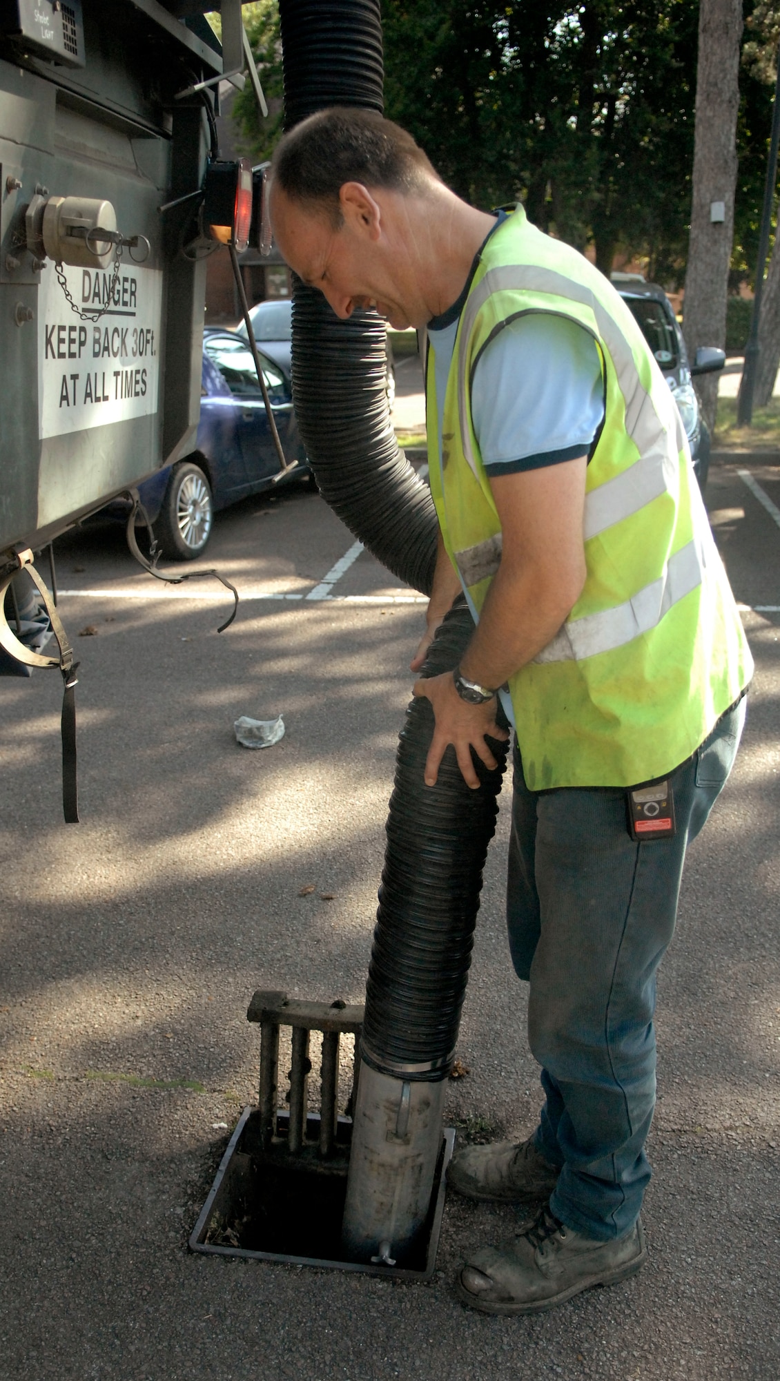 RAF MILDENHALL, England -- Richard "Spot" Austin, 100th Civil Engineer Squadron, vacuums leaves and other debris from a water drain in a parking lot here Aug. 3. (U.S. Air Force photo/Staff Sgt. Austin M. May)