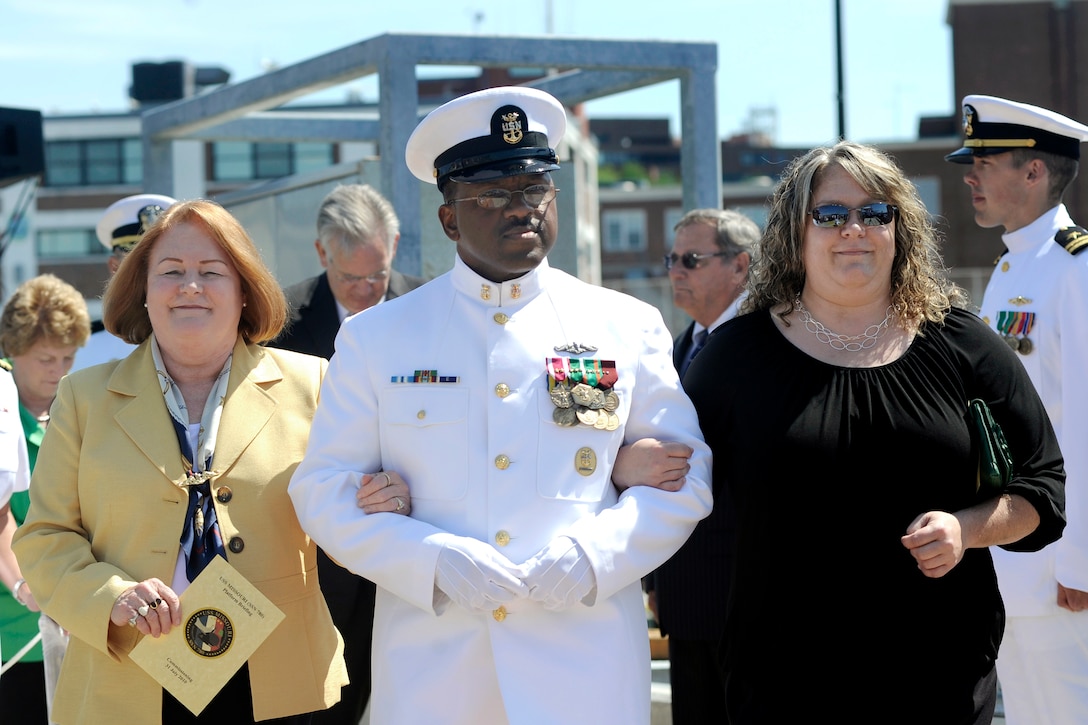 U.S. Navy Command Master Chief Reginald Brown, center, assigned to attack submarine USS Missouri, escorts the ship's sponsor, Rebecca Gates, left, and the ship's matron of honor, Eleanor Gates, at the start of the ship's commissioning ceremony at Naval Submarine Base New London, Groton, Conn., July 31, 2010. The ceremony officially put the ship into active service. 