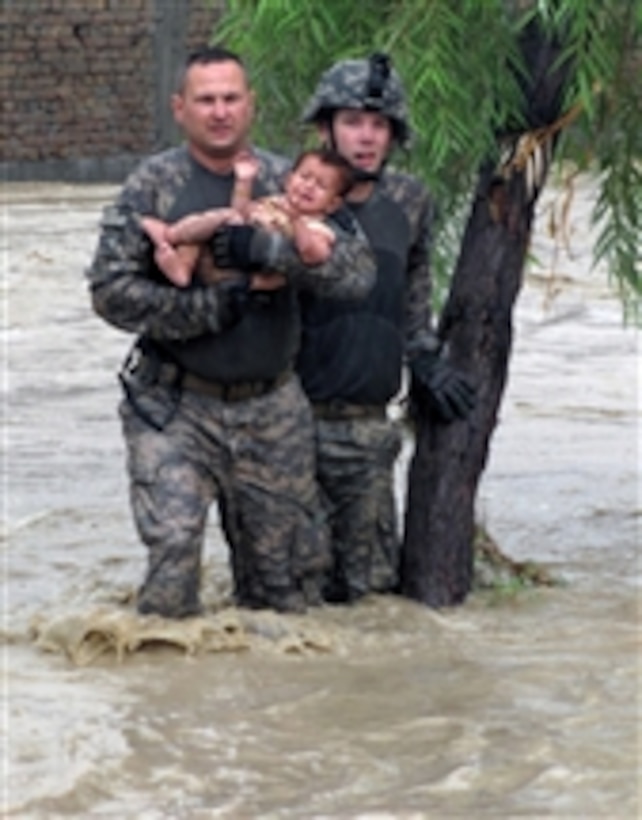 U.S. Army Sgt. Robert Huff and Cpl. Patrick O' Rourke rescue an Afghan child from encroaching flood waters in Nari Shahi village in the Beshood district of the Nangarhar province of Afghanistan on July 28, 2010.  The soldiers are from Military Police Platoon, Headquarters and Headquarters Company, Special Troops Battalion, Task Force Spartan and were returning from a patrol when they stopped to help distressed villagers.  