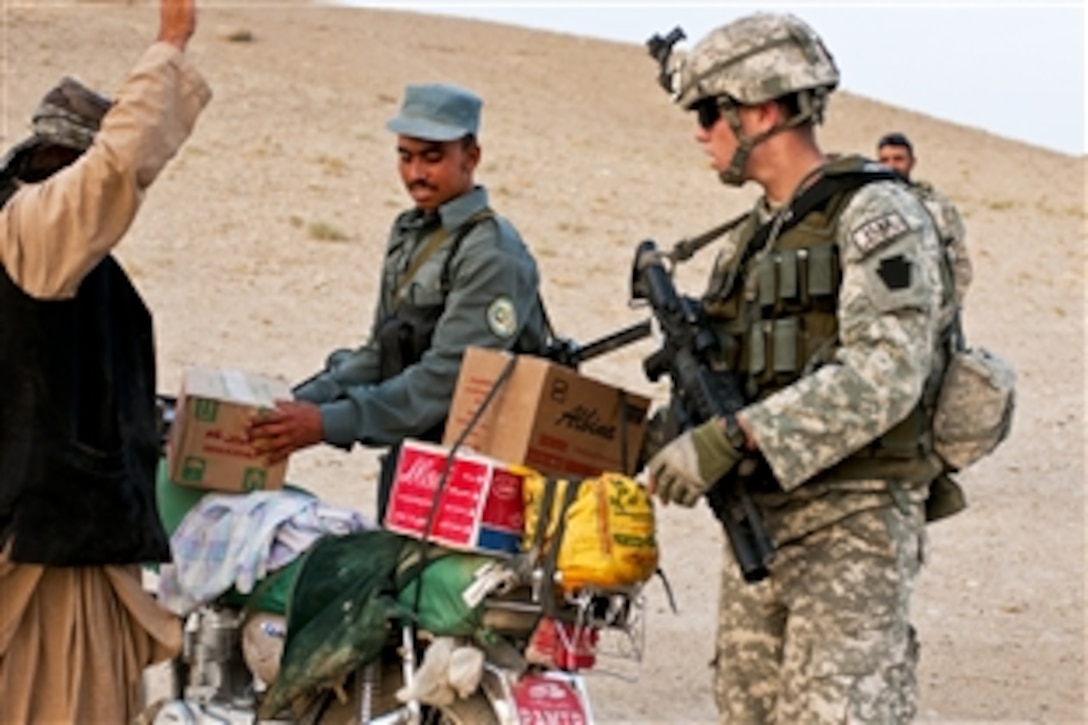 U.S. Army Spc. Nicholas Nutting, right, and an Afghan police officer, center, search an Afghan man and his motorcycle at a traffic control point outside Qalat City in Zabul province, Afghanistan, July 29, 2010. Nutting is a security forces grenadier assigned to the Zabul Provincial Reconstruction Team.
