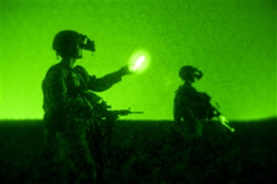 As seen through a night-vision device, coalition members assigned to the Zabul Provincial Reconstruction Team flag down a vehicle for inspection at a traffic control point outside Qalat City in Zabul province, Afghanistan, July 29, 2010.