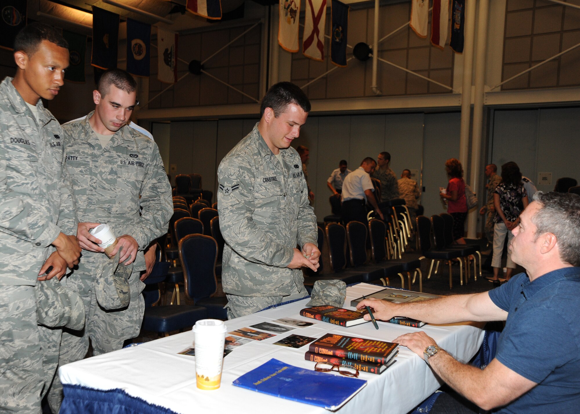 Airman 1st Class Nicholas Crabtree, 22nd Logistics Readiness Squadron supply management apprentice, purchases a book called, “I Killed,” from Bernie McGrenahan, comedian, after the comedy show “Happy Hour,” at the Robert J. Dole Community Center ballroom Aug. 2, 2010, McConnell Air Force Base, Kan.  The “Happy Hour” tour covers the number one substance abuse problem for military installations today--high-risk drinking.  After opening the show with his stand-up comedy routine, Bernie shared the facts of how his college partying got “out of control” and how he turned his life in a positive direction.  McConnell AFB leadership continually research and take advantage of new ways to educate Airmen about living a healthy lifestyle, taking care of their wingmen and their families.  (U.S. Air Force photo/Airman 1st Class Andrea Salazar)