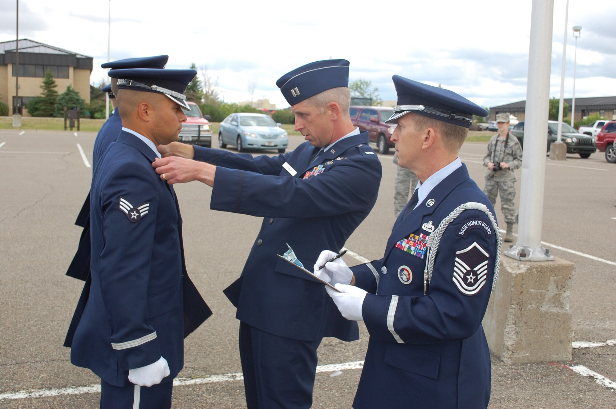 Capt. Craig Lowery, 341st Logistics Readiness Squadron operations officer, inspects the uniform of Senior Airman Rogerio Nascimento, 341st Force Support Squadron force management technician, during the Quarterly Honor Guard All Call at Medal of Honor Park July 23. Master Sgt. Jeffery Parker, Base Honor Guard superintendent, tallies the individual scores. (U.S. Air Force photo/Airman 1st Class Kristina Overton)