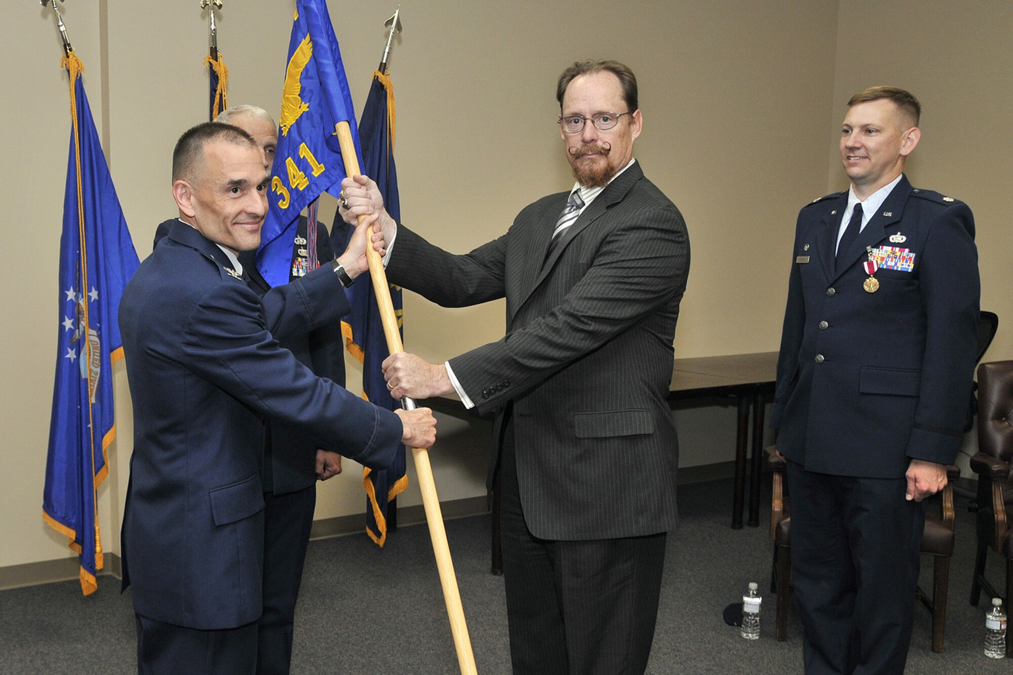 Mr. Randy McFadden, center, formally accepts directorship of the 341st Communications Squadron from Col. John Patricola, 341st Mission Support Group commander, as departing 341st CS commander Lt. Col. Jordon Cochran looks on.  The change of leadership ceremony, held July 21 in building 145’s conference room, also marked the conversion to civilian charge of the 341st Communications Squadron.  (U.S. Air Force photo/John Turner)