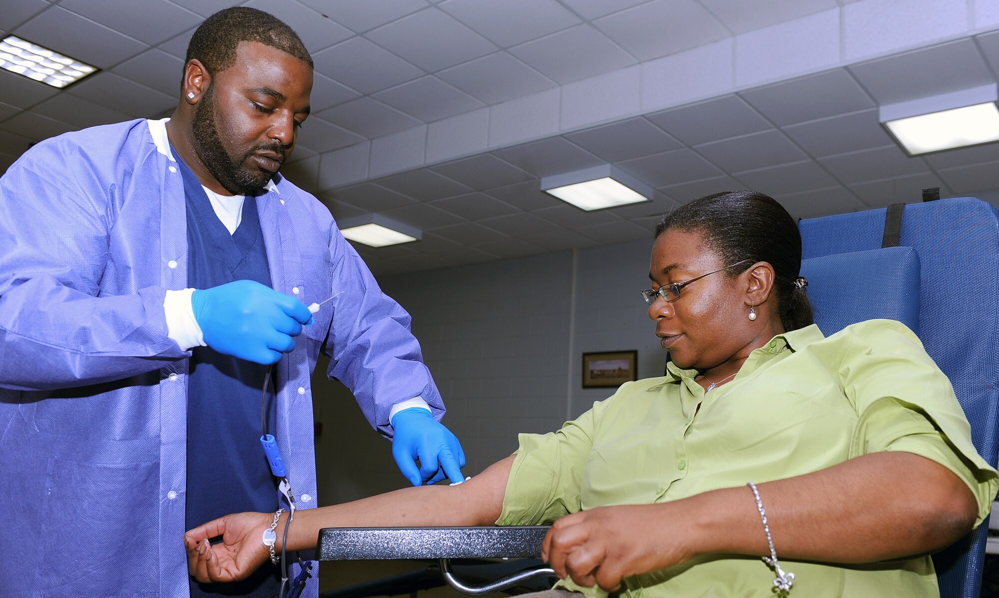 LANGLEY AIR FORCE BASE, Va. -- Daniel Belin, Naval Medical Center Portsmouth phlebotomist, inserts a syringe into Jacqueline Preliou-Holland’s arm at the Community Center during the Armed Services Blood Program blood drive Aug 4. The ASBP plays a key role in providing quality blood products for service members and their families in both peace and war. (U.S. Air Force photo/ Senior Airman Gul Crockett)