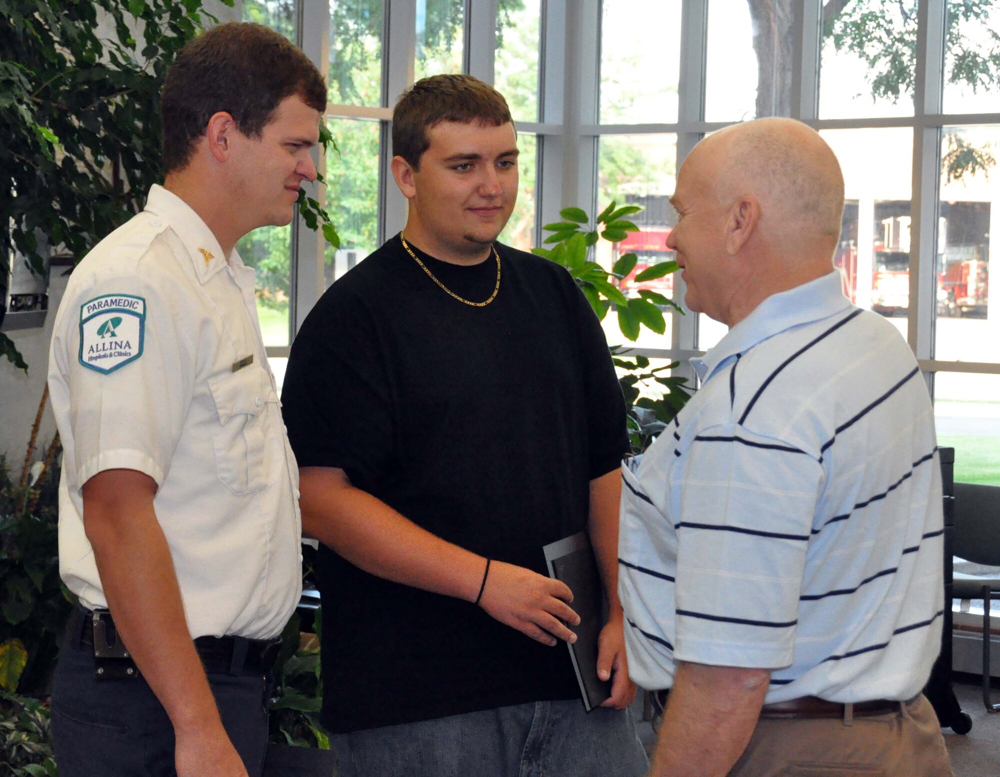 Sam Romain, (center) talks with Terry Hanson (right) whose life he saved by administering CPR before paramedic Ken Derosier arrived at the scene.  Romain, son of Lt. Col. C.J. Bentley, 934th Airlift Wing, receive Chief's Award of Merit  from the Lakeville Police Department Aug. 2. (Air Force Photo/Capt. S.J. Brown)