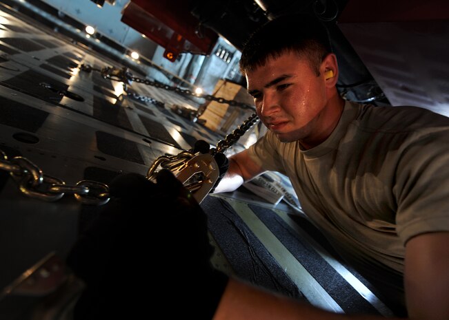 Airman 1st Class Kyle Greer secures a V-2000NG well drilling system to the bed of a C-5 Galaxy cargo plane July 30, 2010, on Joint Base Charleston, S.C. Aerial porters like Airman Greer carefully distribute cargo evenly throughout the aircraft ensuring the cargo does not move freely, causing the aircraft's stability to falter during flight. Depending on the weight and size of the cargo, different configurations are used to tie down the cargo. Airman Greer is a air transportation specialist with the 437th Aerial Port Squadron. (U.S. Air Force photo/Senior Airman Timothy Taylor)