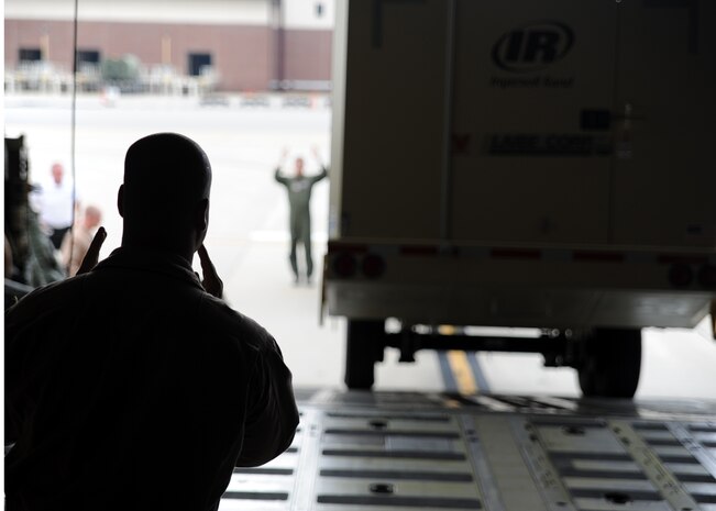 A loadmaster with the West Virginia Air National Guard signals his counterpart directing a forklift operator to proceed forward into a C-5 Galaxy cargo plane July 30, 2010, on Joint Base Charleston, S.C. Clear communication between loadmasters and vehicle operators loading cargo is critical for safe cargo handling, as operators move cargo weighing several tons into the confined space inside aircraft. (U.S. Air Force photo/Senior Airman Timothy Taylor)